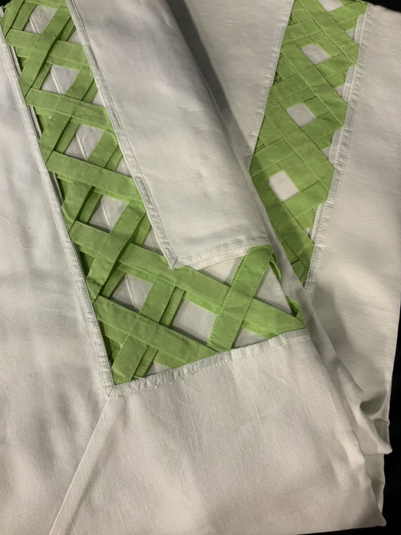 Decorative Tablecloth with Green Trim: large table cloth in white with a green peek-a-boo basket pattern around the edge of the table where it hangs over the side of the table, made of linen the basket pattern is in a lime green, this tabl