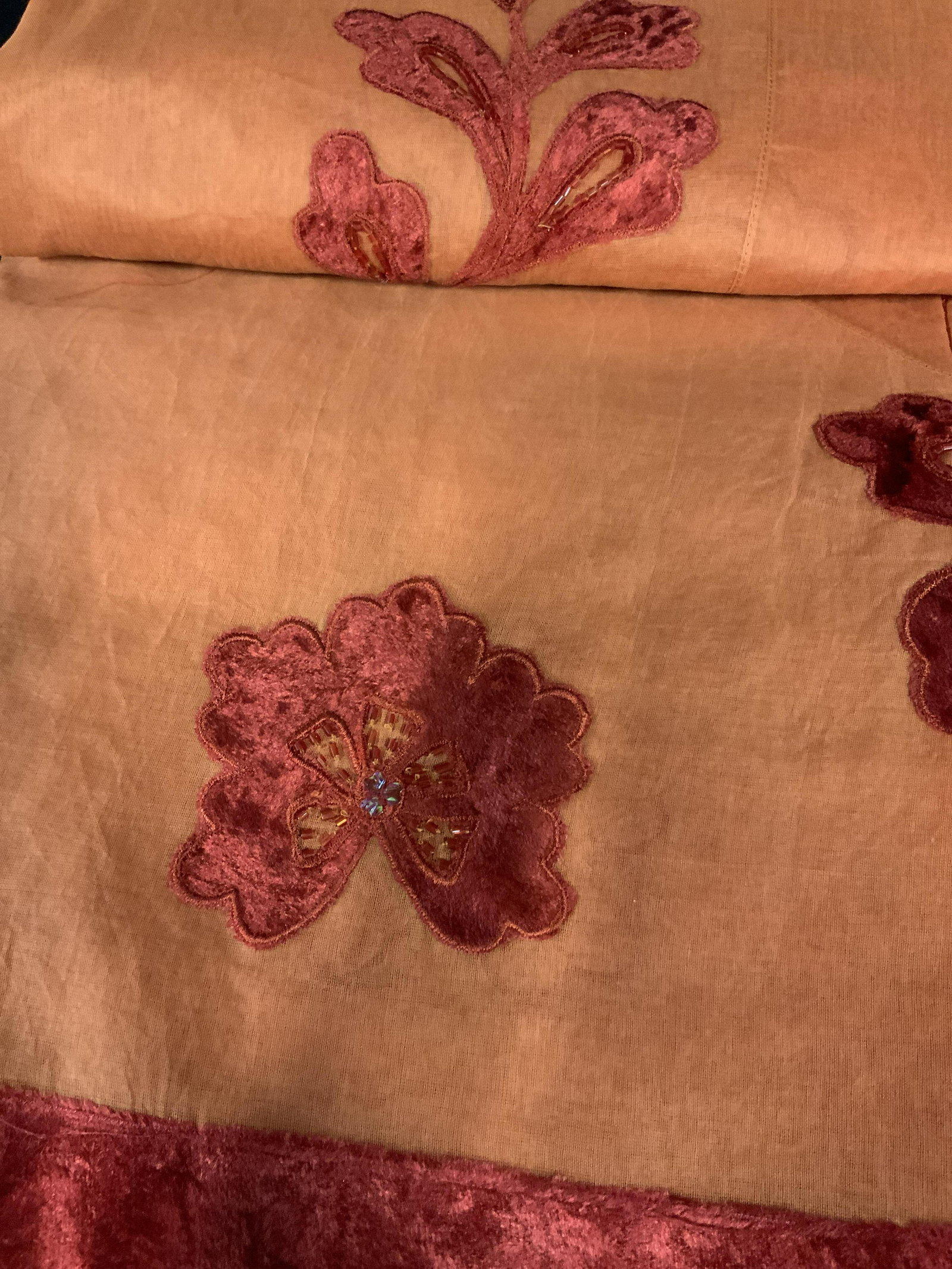 New in packaging set of Two Decorative Tablecloths: large table cloths in orange with a red felted velvet floral pattern and beading around the edge of where it hangs over the side, made of composite fabrics, this table cloth comes with its own sheer f