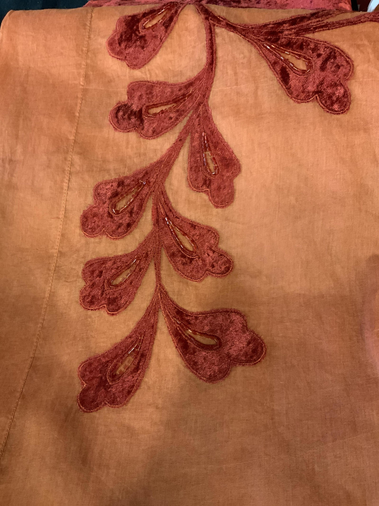 New in Packaging Set of Two Decorative Tablecloths: large table cloths in orange with a red felted velvet floral pattern and beading around the edge of the table where it hangs over the side, made of linen the this table cloth comes with its own fabric