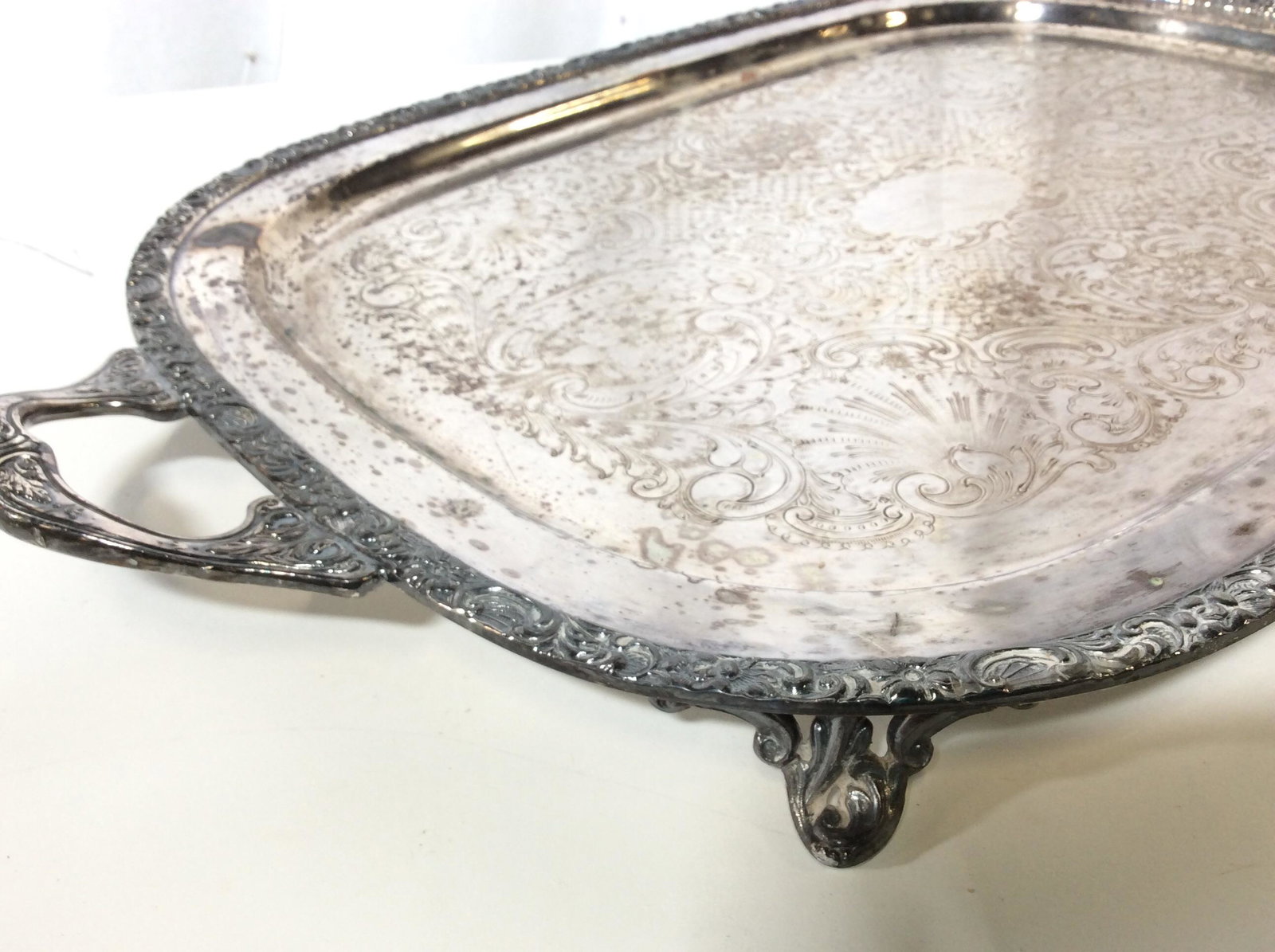 Lot 2 VINTAGE Plated Serving Trays: Detailed art Nouveau or rococo revivals . Oversized footed tray with handles, 27 in L x14 in W x 2.5 in Ht. Many Scroll and floral patterns. Round serving tray , heavy rim detail in relief, underside 