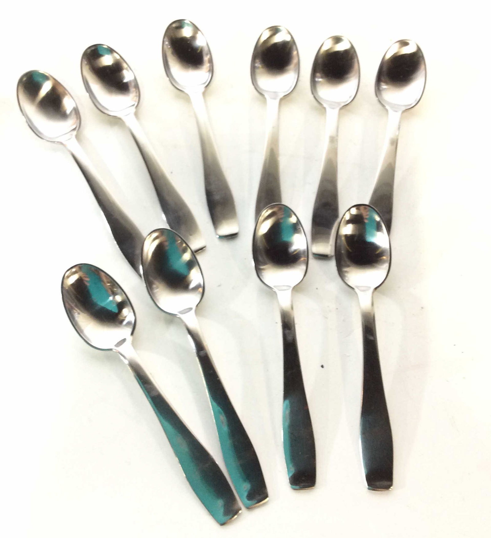 GEORG JENSEN DESSERT SPOON SET, 10, DENMARK: Stainless steel dessert or cocktail spoons. Minimalist Style. Comes with flatware Keepsake cloth. 10 spoons, 4 3/4 in long. All marked GEORG JENSEN’S Stainless Steel Made in Denmark. Vintage. Very g
