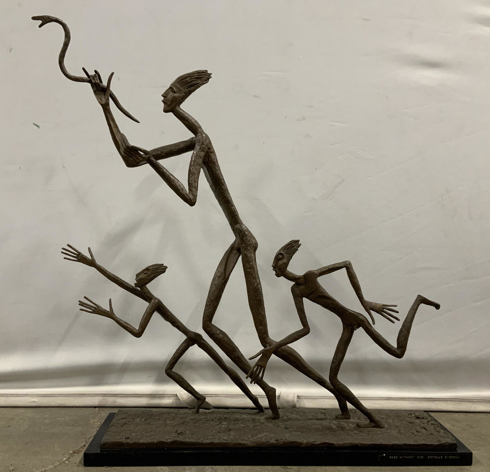 Abstract Bronze Figural Nude Male Sculpture 1964: A signed, titled and dated Estelle Goodman (1930-2007, American) signed and dated bronze multi figure sculpture of three nude men each running while the central figure holds a serpent. The three male 