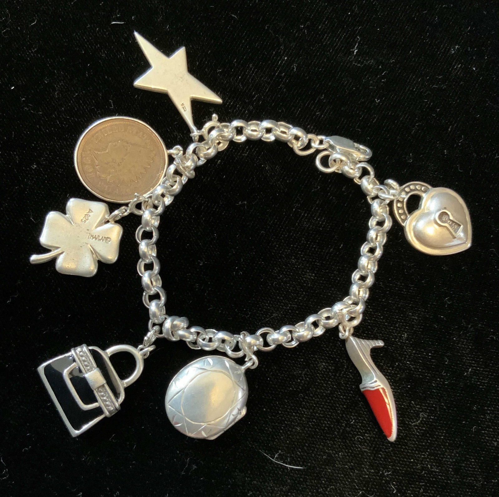 Vintage Sterling Silver Charm Bracelet: 7 charms each marked for Sterling Silver, chain measures app 7 inches, charms include, etoile star, coin with Native American chief as encased coin, 4 leaf clover, enamel and silver purse, starburst e