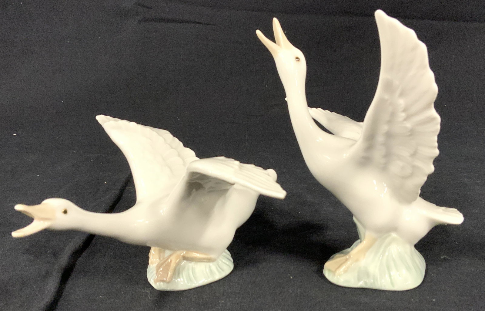 Pair LLADRO Porcelain Duck Figures, Spain: This is a pair of porcelain swans. Each piece depicts a swan with its wings and neck extended. The statues come from LLADRO, and are made in Spain. The underside reads LLADRO, HANDmade IN SPAIN, DAISA