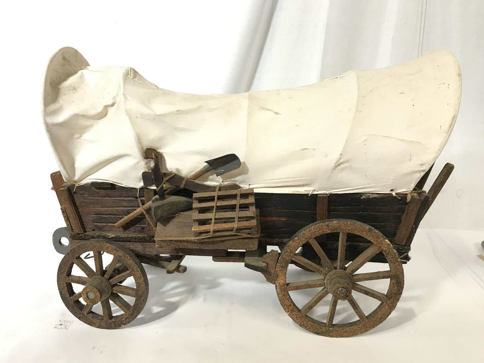 Wooden Western Stage Coach Wagon: Wooden folk art wagon, piece is vintage possibly antique. Includes miniature rifle, horse yokes, saddle, travel bag. Measures approx 12.5 inches H, and 17 inches long. Wear is consistent with age. Wes