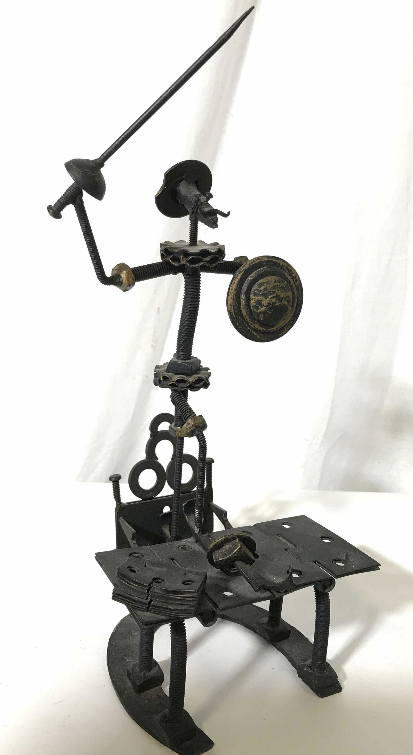 Vintage Folk Art Metal Figure: Metal figure, possibly vintage, possibly antique. Depicts a mustached man crafted from nuts and bolts, wielding a sword and shield. Gilt paint highlights parts of the sculpture. Wear is consistent wit