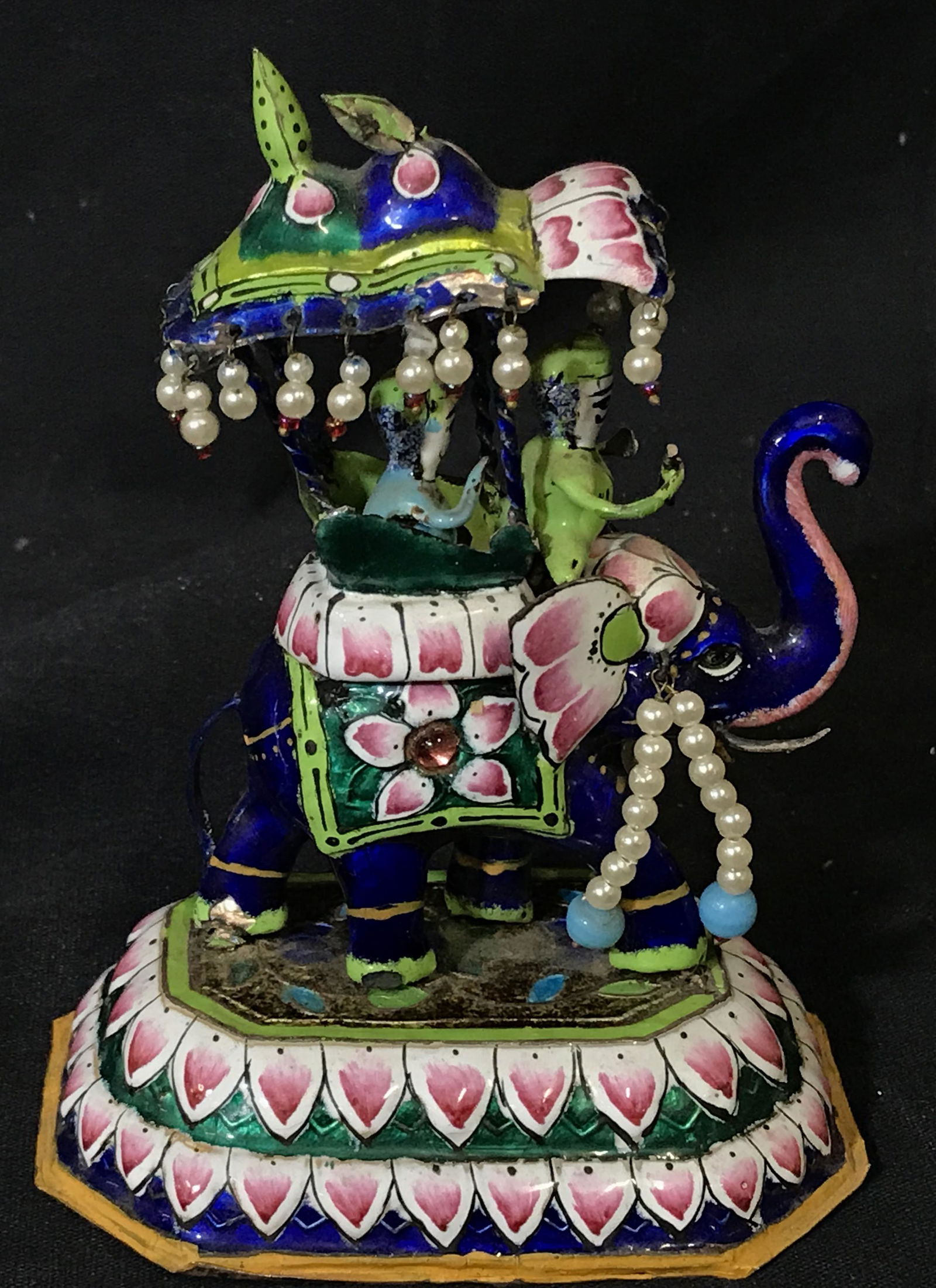 colorful Indian Elephant Figurine: Elephant figurine, enameled metal over unknown material. tin plating to bottom, Pearl style tassel beading throughout, measures 5.25 inches at tallest point, subject two figures riding an elephant, El