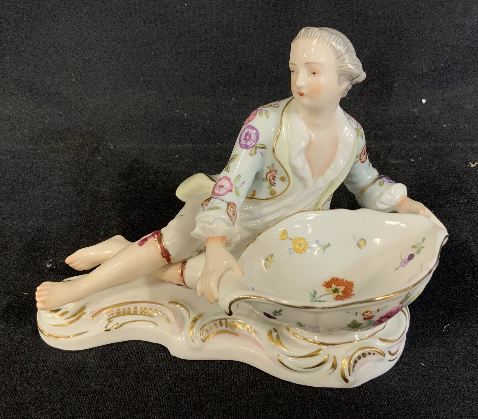 Pair Rococo Styled Porcelain FIgural Dishes: Pair French Rococo styled porcelain dishes with stamps to underside, Stamp unidentified, A male and female figure in vegetal motif patterned clothing over a dish, Female figure measures 4 3/4 inches x