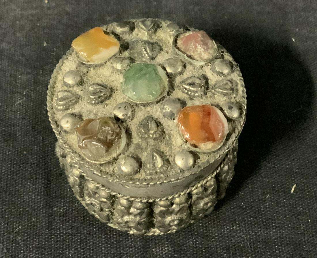 Hand Crafted Ornate Trinket Box: Silver toned metal trinket box with blue velvet interior, No apparent signature or inscriptions, Multi colored stones set into lid and repousse on body of box, Measures 1 1/4 inches x 1 5/8 inches, Tr