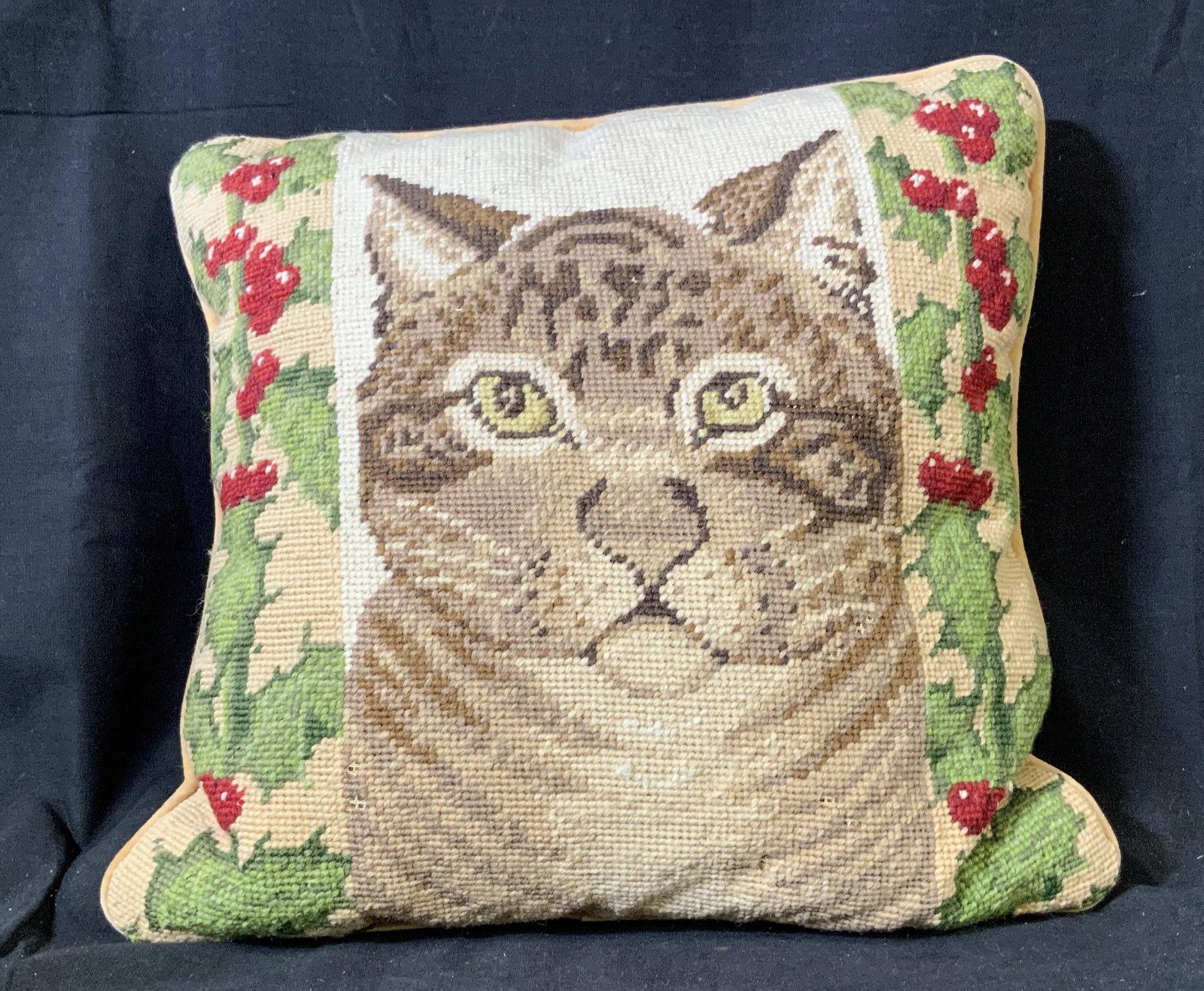 Vintage Holiday Cat Needlepoint Throw Pillow: Vintage needlepoint / cross stitched throw pillow with light orange velveteen backing, cat portrait with holly along the borders, zipper at base of pillow, needlepoint has frayed in some areas but ove