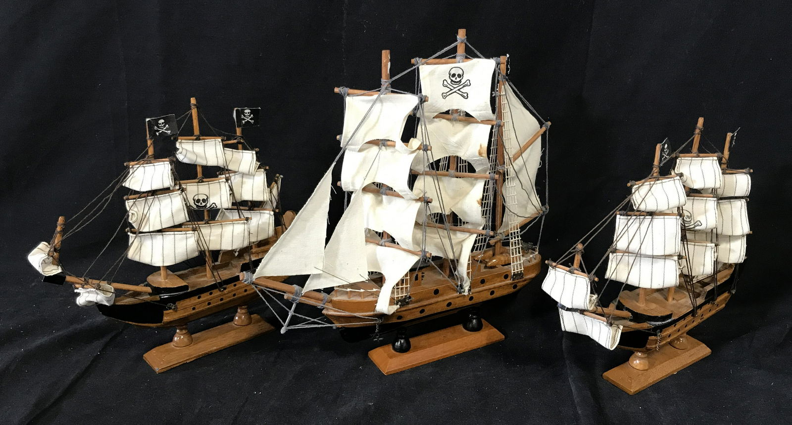 Group Three Model Pirate Ships: Group of three Model pirate ships made of wood with metal embellishments string and sails made of cloth, each is seated on a wooden platform, largest platform measures 5.25 inches by 1.5 inches, large