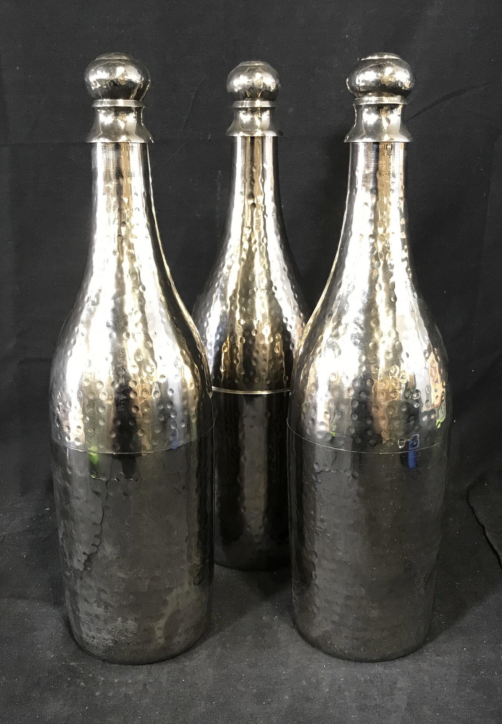 Set Three Decorative Metal Bottles: Set of three decorative metal bottles, all bottles done in a silver toned metal that has been hand stamped, each open at the center with a twist lock, all have labels to underside only one is still le