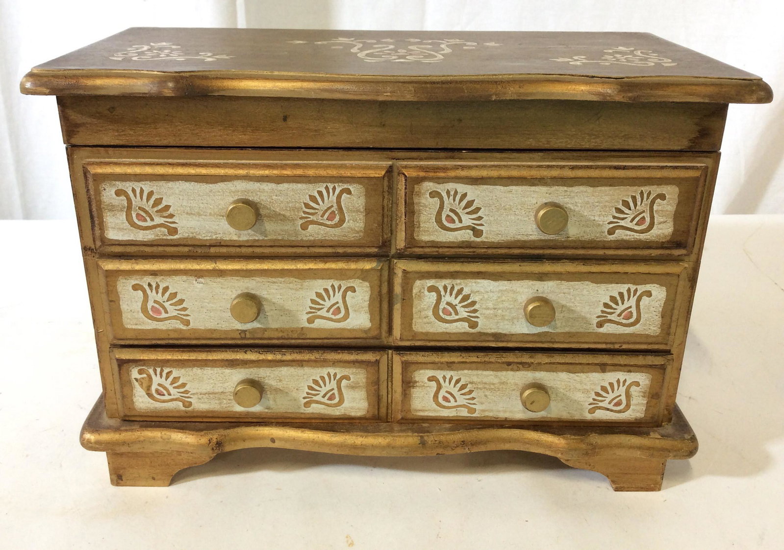 Victorian Style Hand Painted Jewelry Box: Gilt wash, Embossed stenciling with a white wash overlay, 3 drawers bottom length of box, center individual. Lid on hinge with mirror, velvet sienna color lined interior. 10.75 in. L x 5.5 in. W. Musi