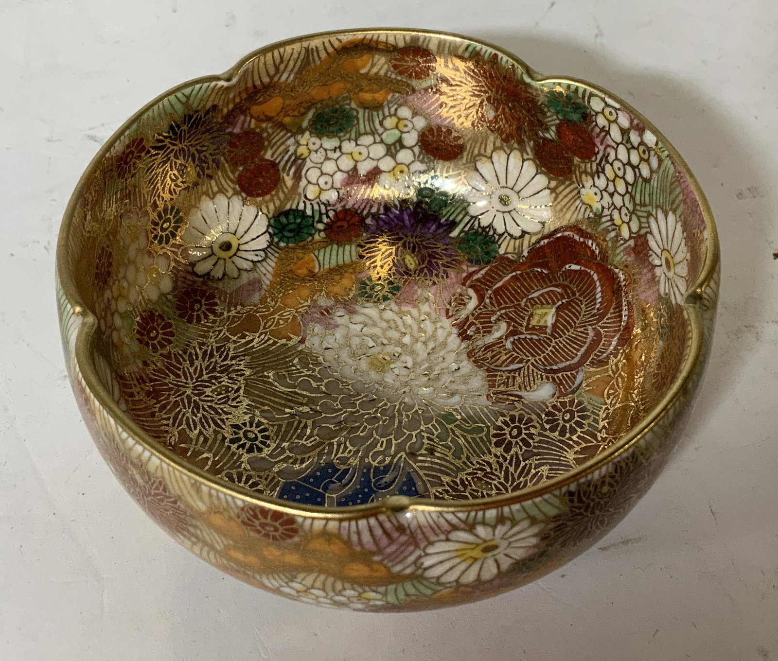 Chinese Floral Decorative Bowl: Chinese floral decorative bowl with painted gold detailing, stamp to base in Chinese characters, vibrantly colored flowers, rim of bowl creates floral motif, in good condition, Measures 3 5/8 inches i