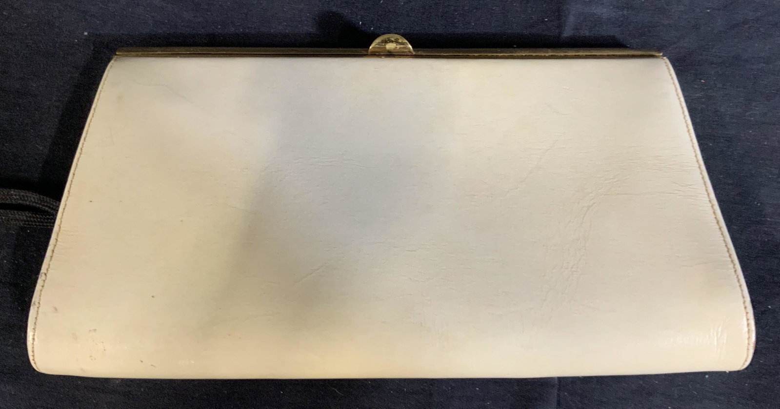 White Vintage Saks Clutch: Vintage White leather clutch, make by Saks 5th Avenue, purse has gold colored figure and an alligator mouth closure, inside in pink silk is one slit pocket and one zippered pocket both lined with blac