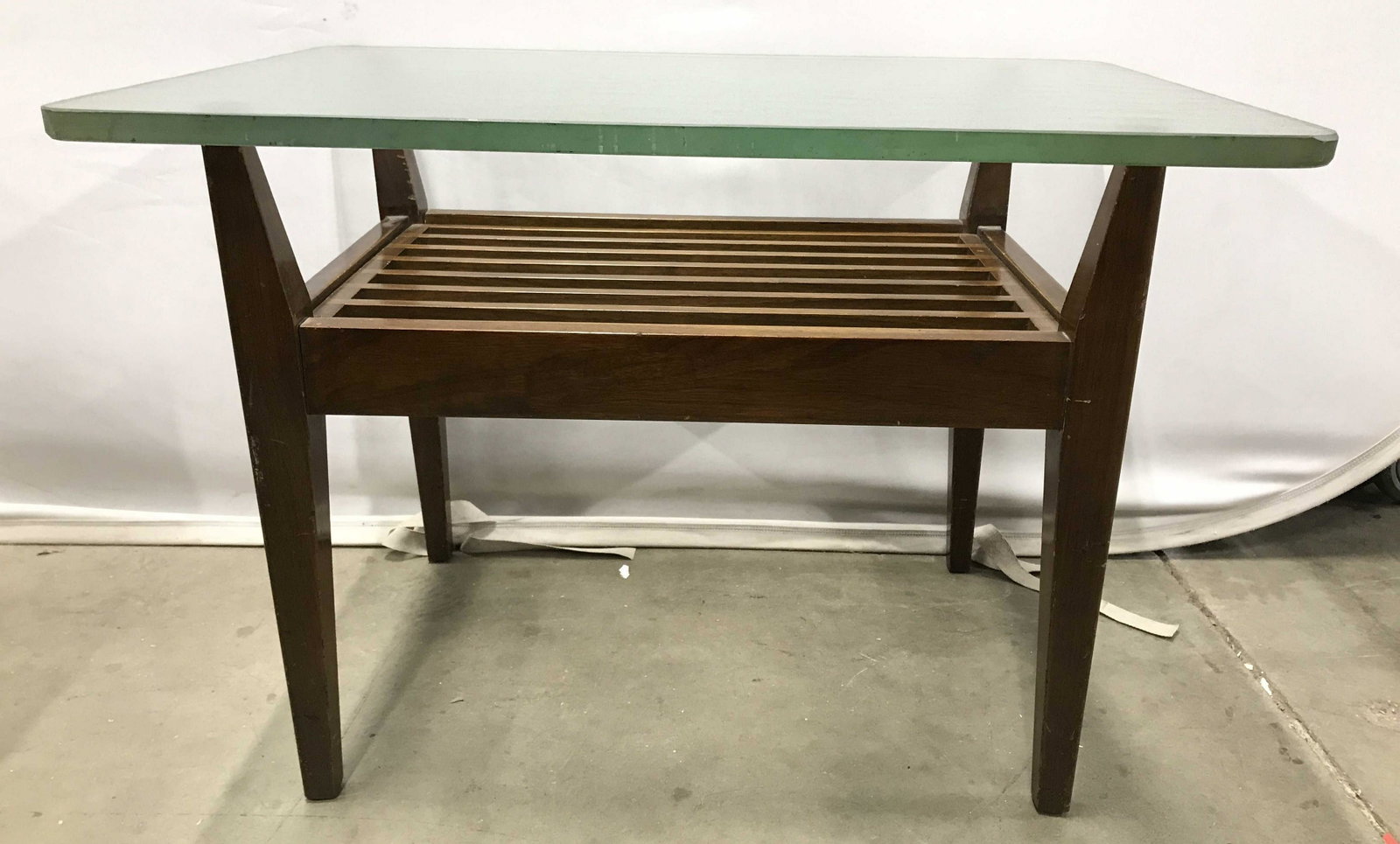 Mid Century Modern Glass Top Side Table: Side table has wooden base and thick glass top. Piece measures approximately 30 inches long 21 inches tall 20 inches deep. Center piece with cornered rungs is removable. Side table, end table, mid cen