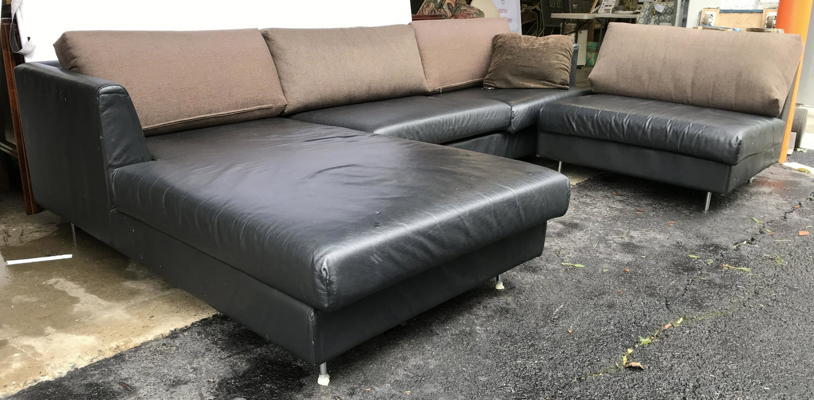 THE Black Toned Leather Sectional: Tag on piece reads THE. Sectional is black toned. Piece appears to possibly be genuine leather. Piece has metal feet. Includes brown toned upholstered backrest cushions. Sofa, couch, sectional, leathe