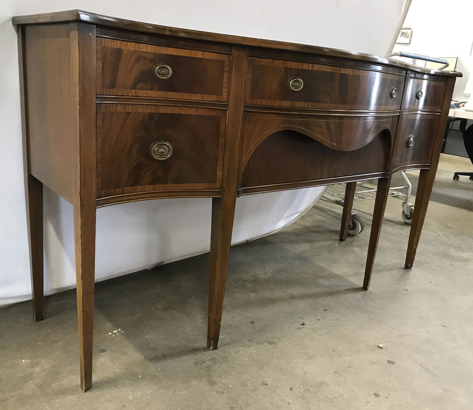Serpentine Style Mahogany Bow Front Side Board: Buffet is wooden. Piece appears to be vintage. Piece has bow front. Piece measures approximately 68 inches long 38 inches tall 24 inches deep. Each drawer has gold toned brass handles. Buffet has 5 dr