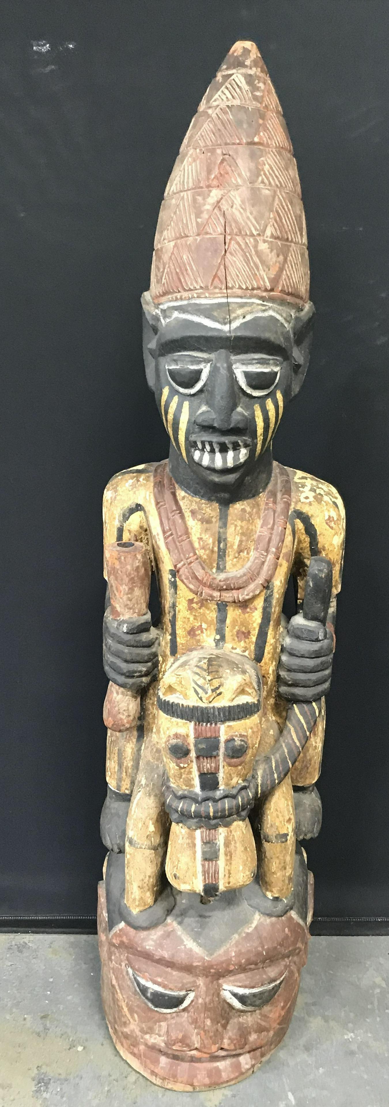 African Hand Carved Wooden Equestrian Statue: African Hand Carved Wooden equestrian statue, painted with brown red yellow black and white pigment, Statue depicts a figure seated on what appears to be a horse holding the reins in one hand and a ho