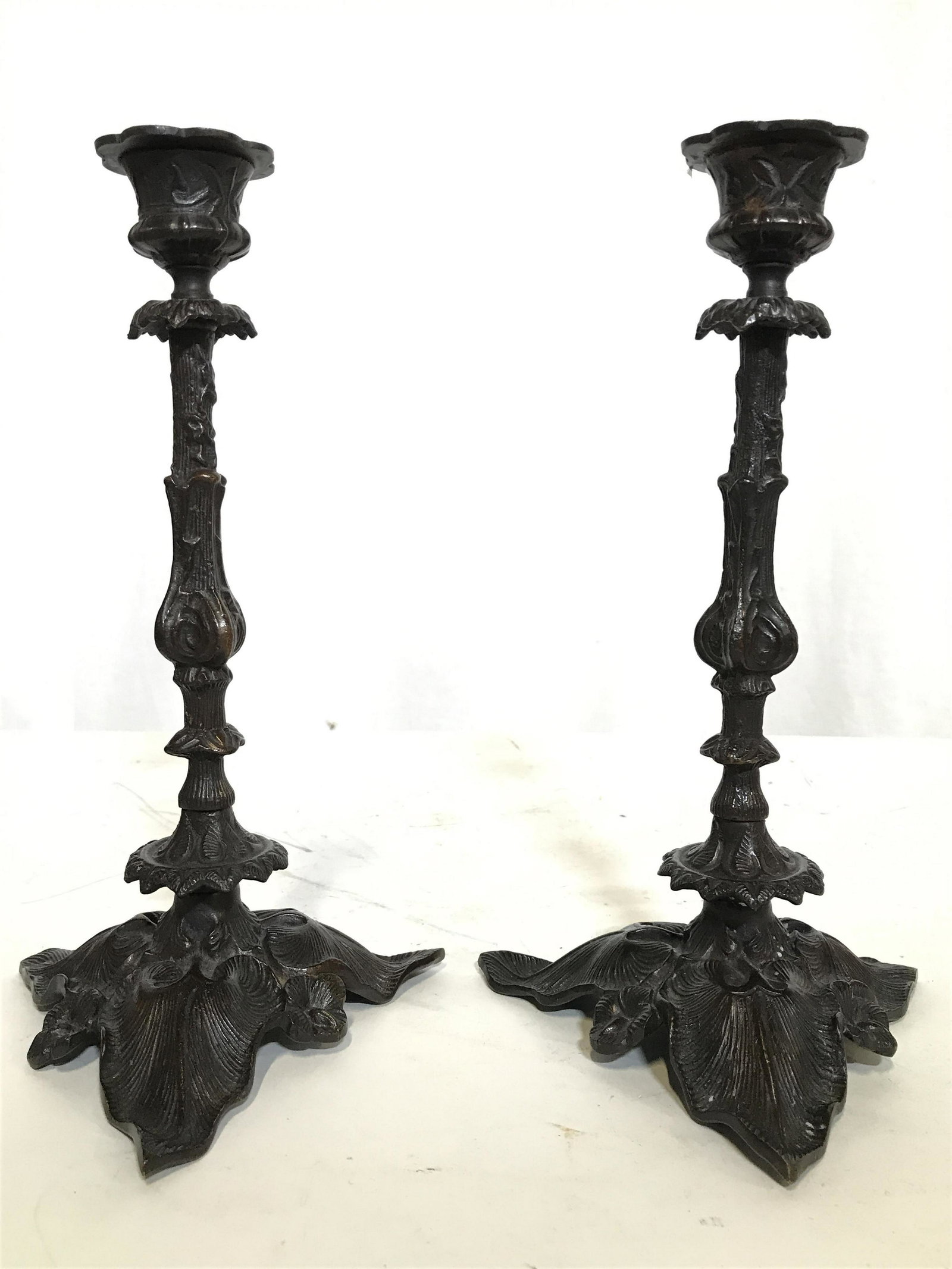Pair Bronze Toned Metal Candlesticks: Candlesticks are bronze toned possibly bronze. Each have floral and leaf structure detail. Candlesticks, Metal candlesticks, tableware, tabletop accessories, tabletop decor. Pieces measure approximate