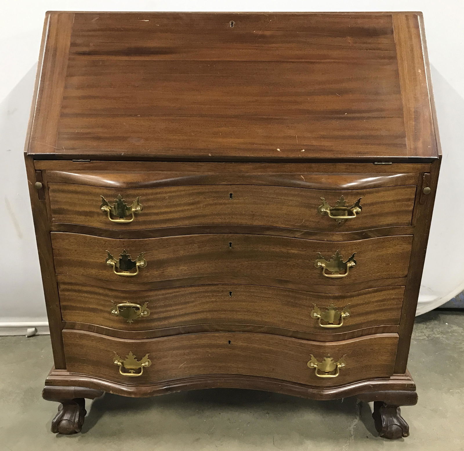 Vintage Wooden Writers Desk: Writers desk is vintage possibly antique. Piece Contains carved ball & claw feet. Top of piece has flip open desk area with supports. Desk has 4 drawers each with gold toned brass handles. Piece measu