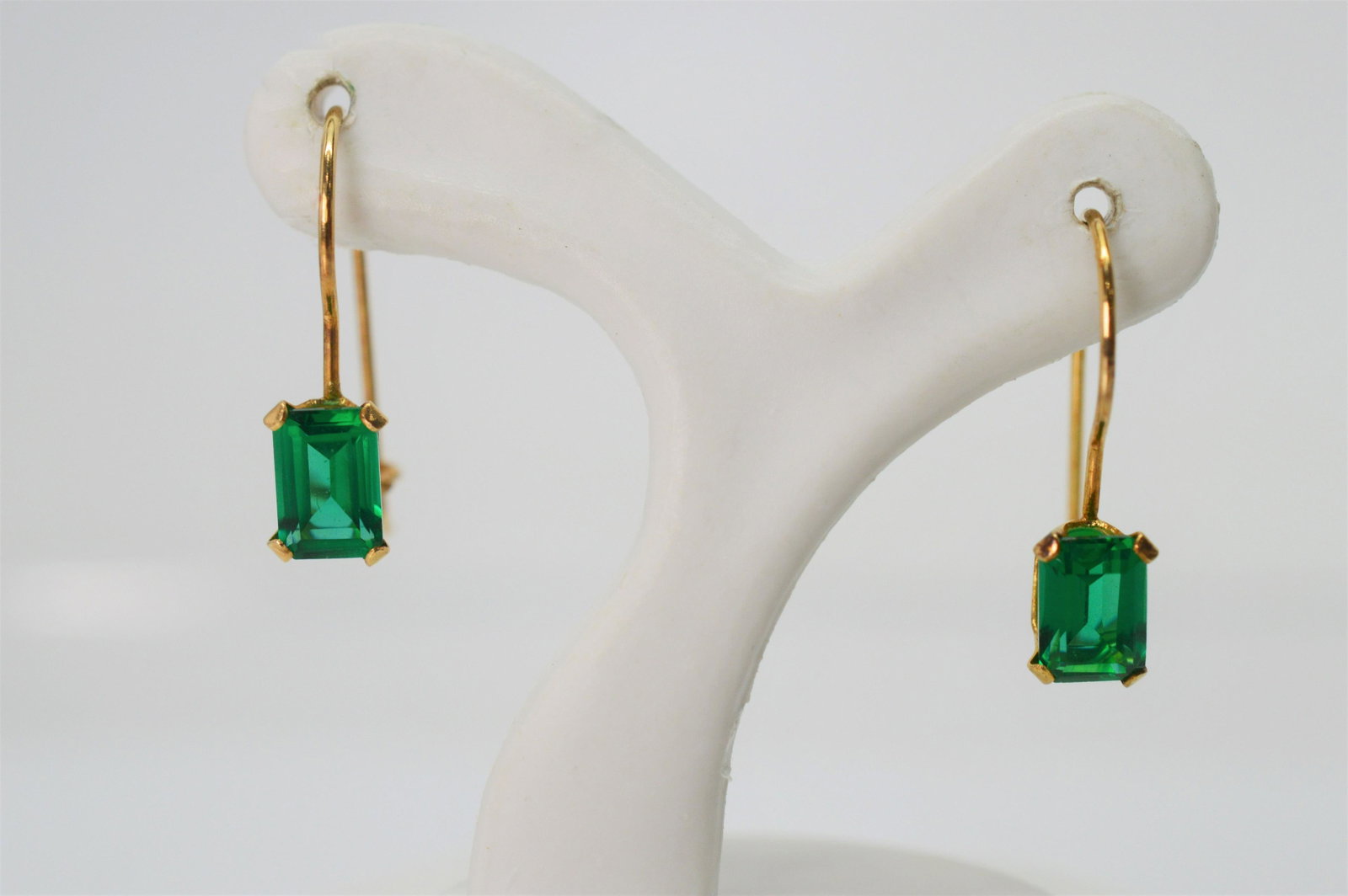 Brilliant Green Beryl Doublet 14 Karat Earrings: 5/8 inch long. Simple in style with intense color impact. Green beryl doublet earrings with two .10 carat emerald cut stones. With hook style closures for pieced ears. 5/8 inch from top of hook to bot