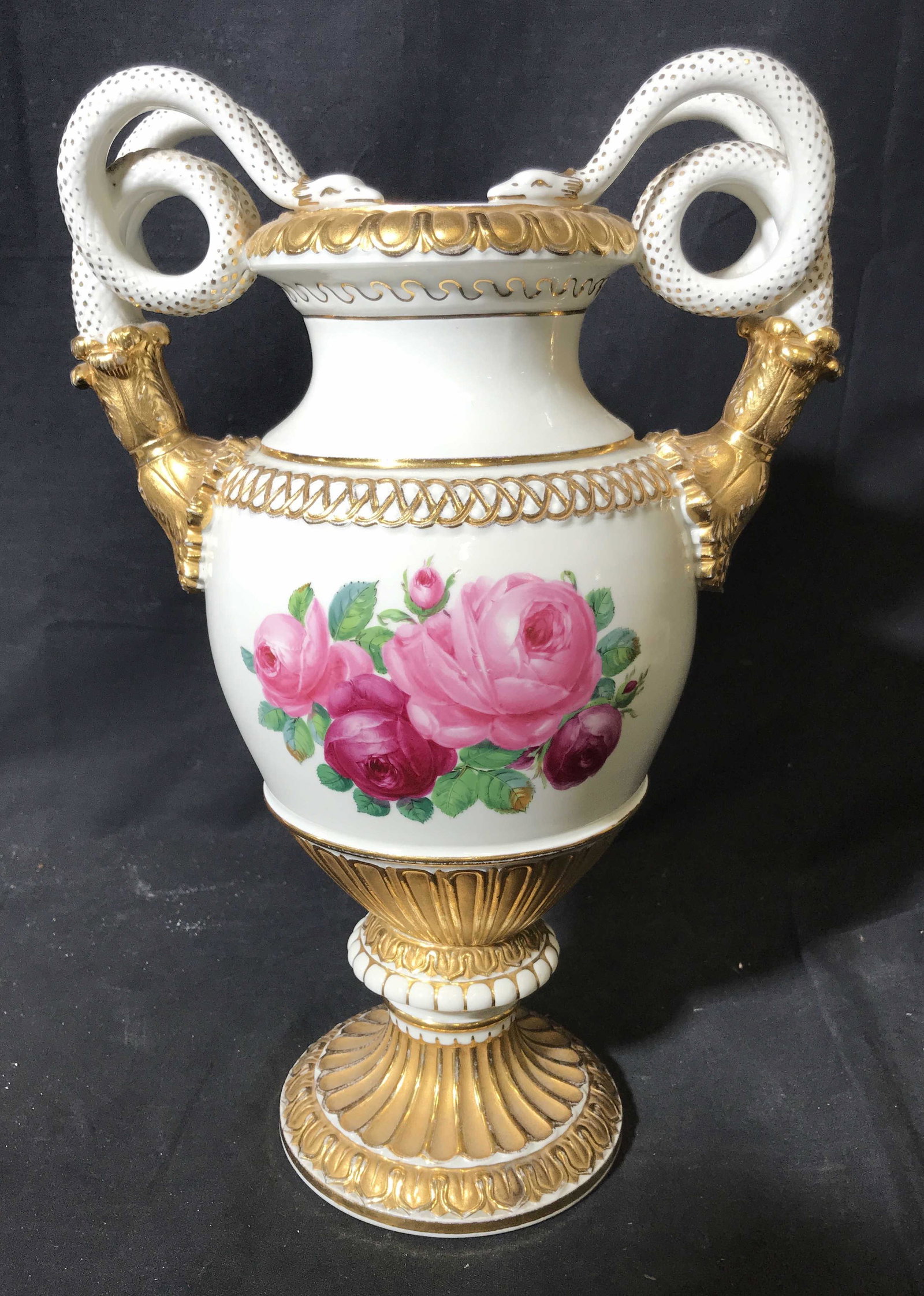 Meissen Porcelain Amphora Vase: Meissen Porcelain Amphora, gilt porcelain along the base handles and decor, floral designs to either side, handle are made in duel snake shaped designs, measures 25 inches at tallest point, stamp to u