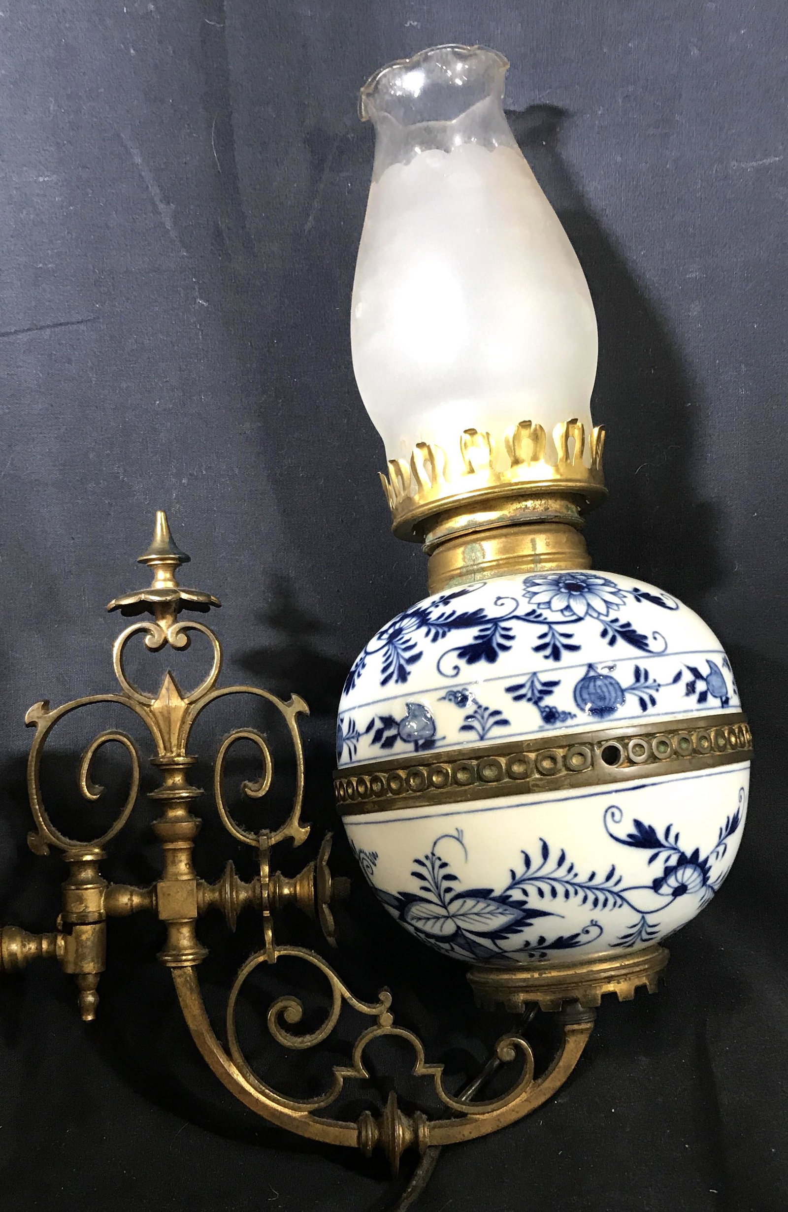 Porcelain & Brass Antique Victorian Sconce: Detailed pierced brass scrolls and Fleur de Lis design, retrofitted for a modern lightbulb, originally an oil lamp sconce. Blue and white porcelain orb, mills surface crack to underside, Measures 12 i