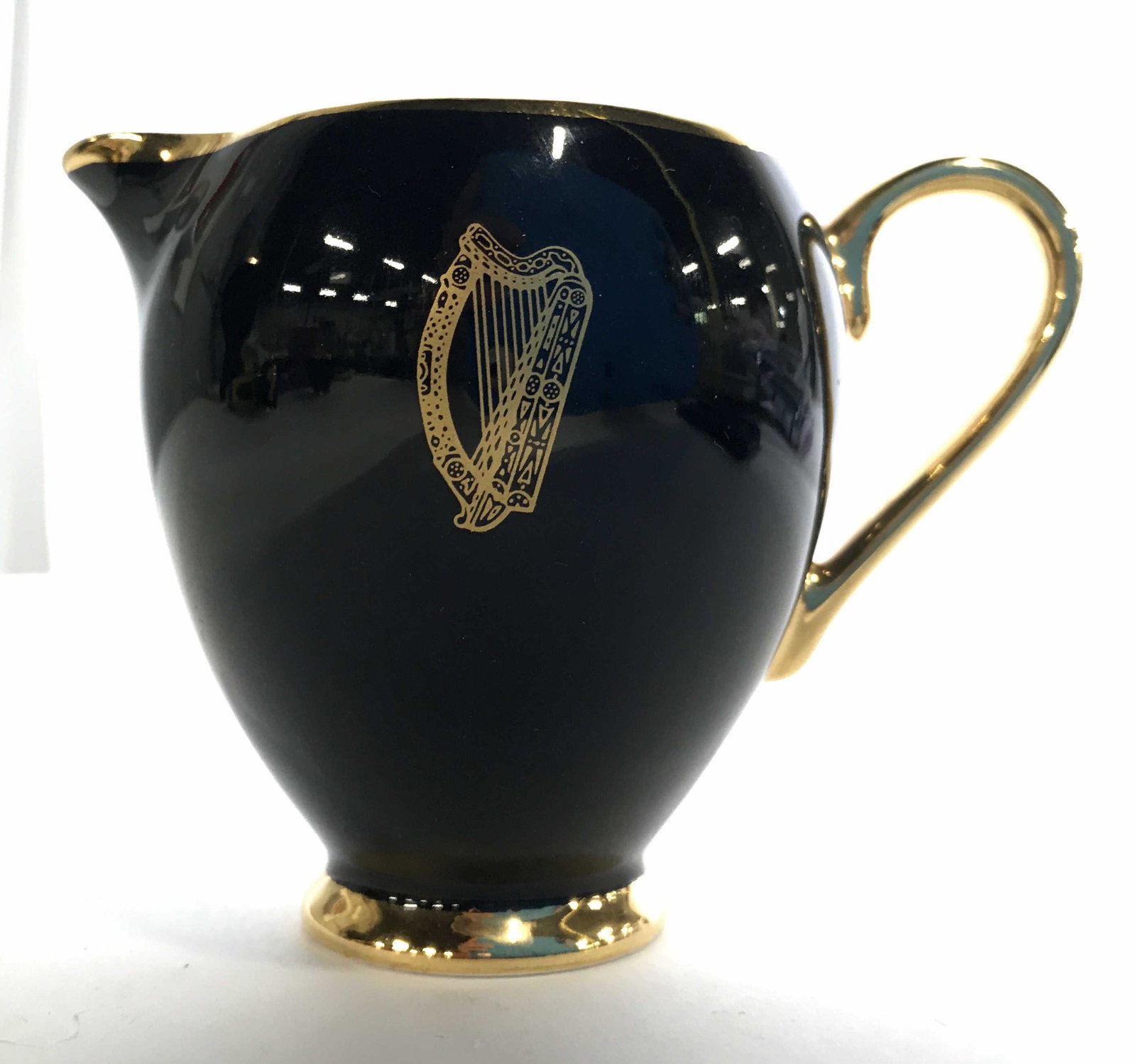 Set 4 ARKLOW Harp Detail Partial Tea Set: Underside of pieces are marked ARKLOW IRELAND. Lot includes 1 saucer, 1 teacup, 1 creamer dish & 1 sugar dish. Saucer measures approximately 5 inches wide. Each piece is black with gold toned harp det