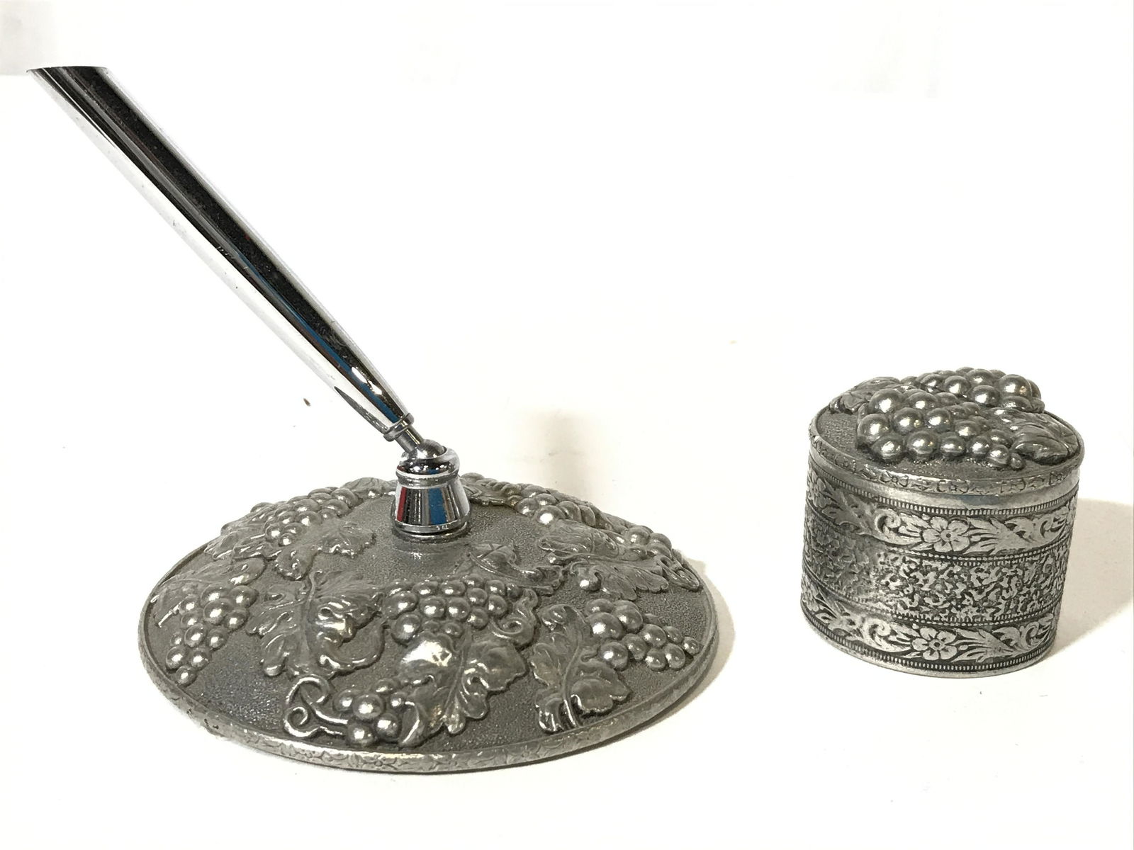 HERITAGE Pewter Penholder & Inkwell: Undersides are marked HERITAGE METALWORKS. Each piece is pewter. Lot includes pen holder and inkwell. Each have beveled grape, leaf, and vine, detail. Piece measures approximately 3.5 inches wide and