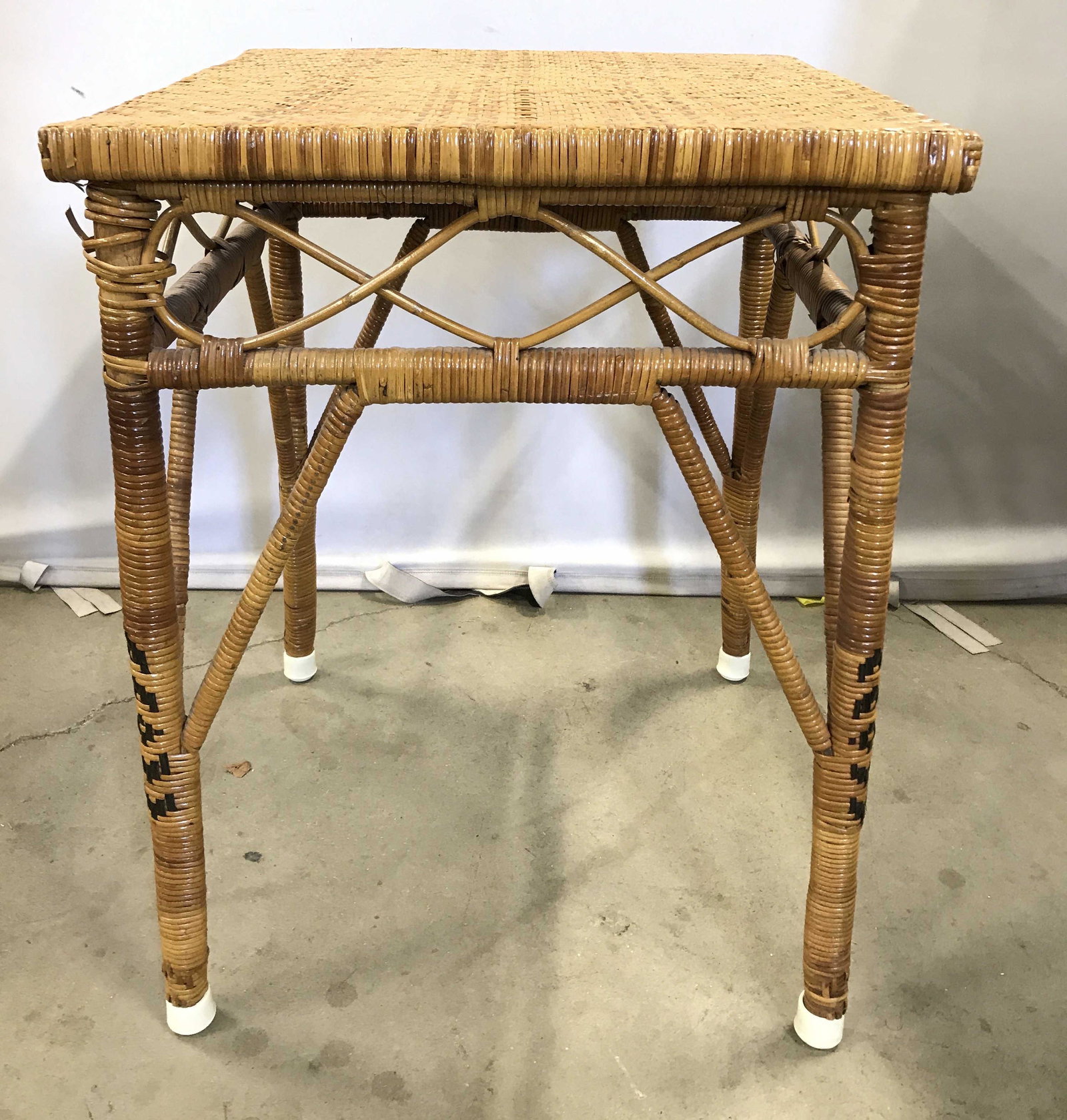 Woven Wicker Side Table: Woven wicker table, woven around wood frame,possibly vintage. Blackened wicker is woven into each leg, each leg is capped. Measures approx 27 inches H, 20 inches W, and 20 inches deep. Wear is consist