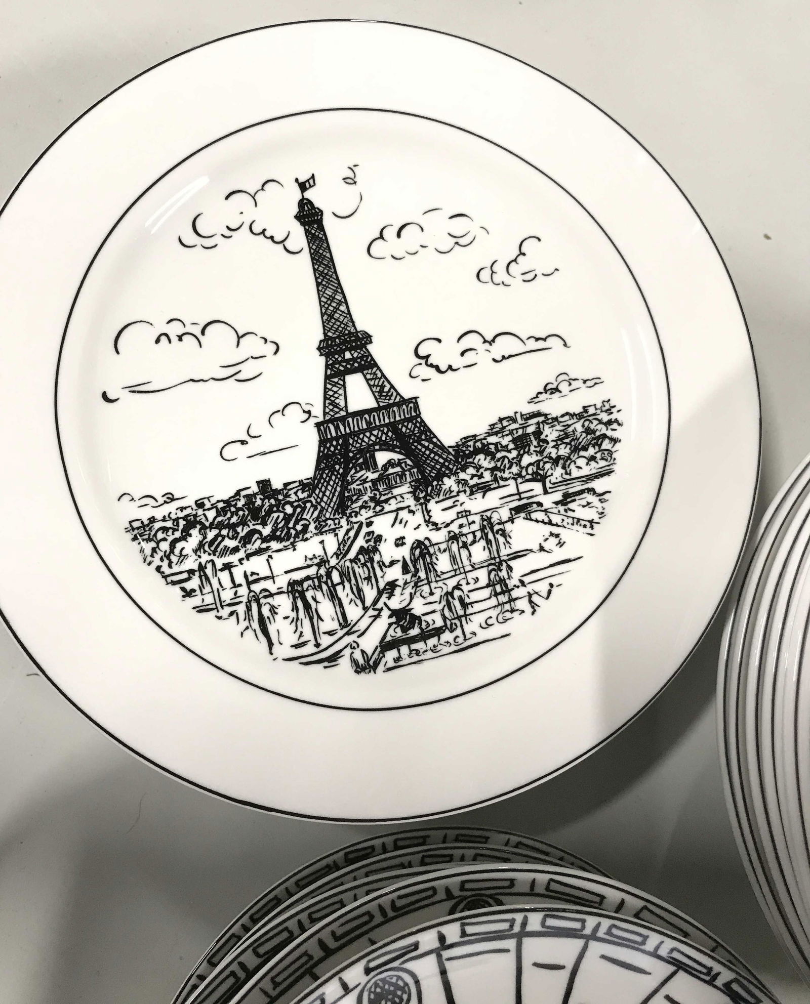 MIKASA Parisian Scenes Fine China Dinnerware Set: Lot consists of black and white cafe, street art scenes and Eiffel Tower. 8 dinner plates, 10.5 in. 8 pasta bowls, 8.25 x 1.75 in. 8 Salad plates. 6 coffee mugs and 8 coffee saucers. All hall marked,