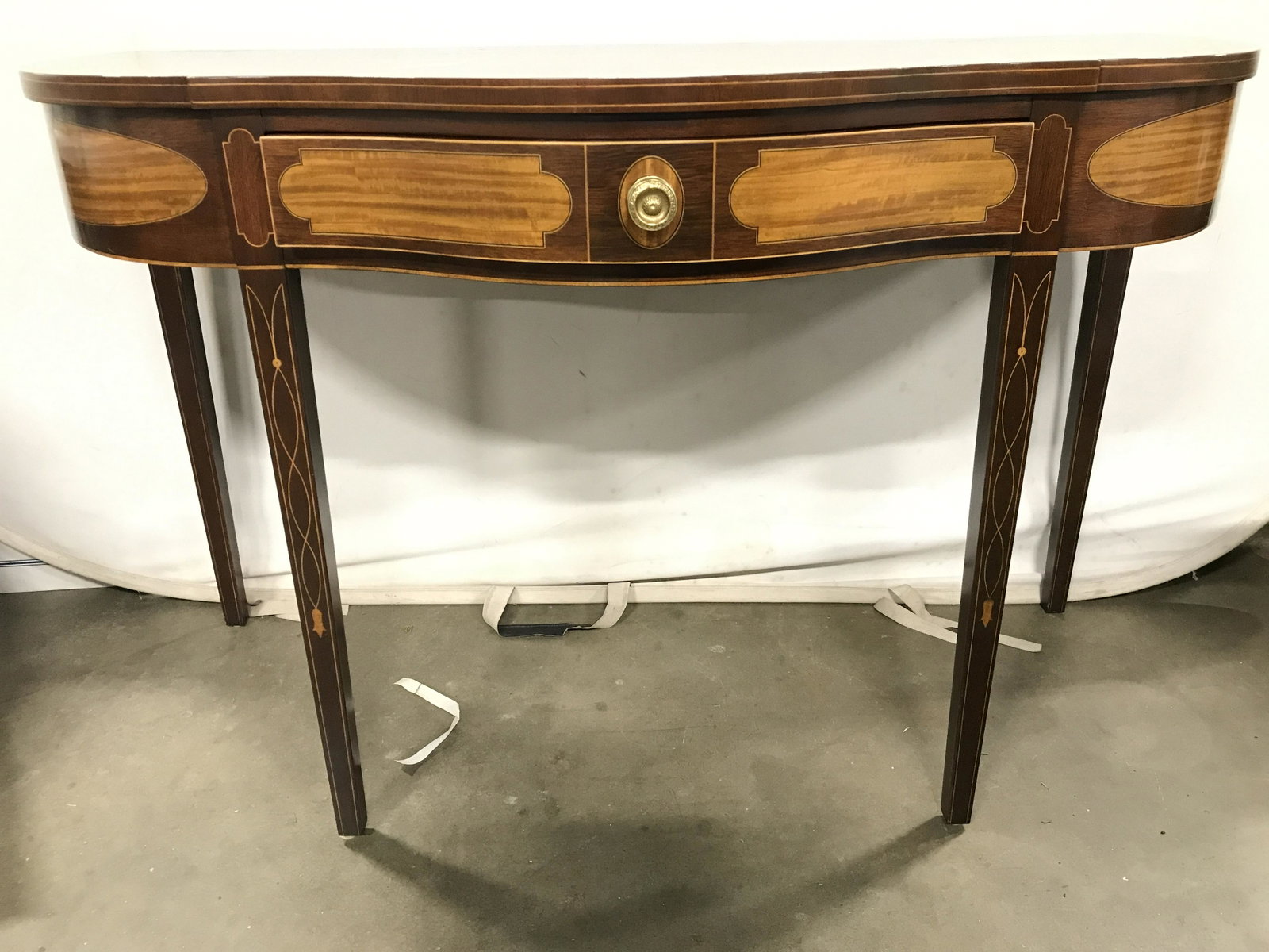 CHRISTMANS WINTERHUR Inlaid Demilune Table: Interior of drawer reads CHRISTMANS WINTERHUR. Piece appears to have inlaid wooden detail. Piece has 1 drawer with gold toned knob style metal handle. Drawer has hand dovetailing. Piece measures appro