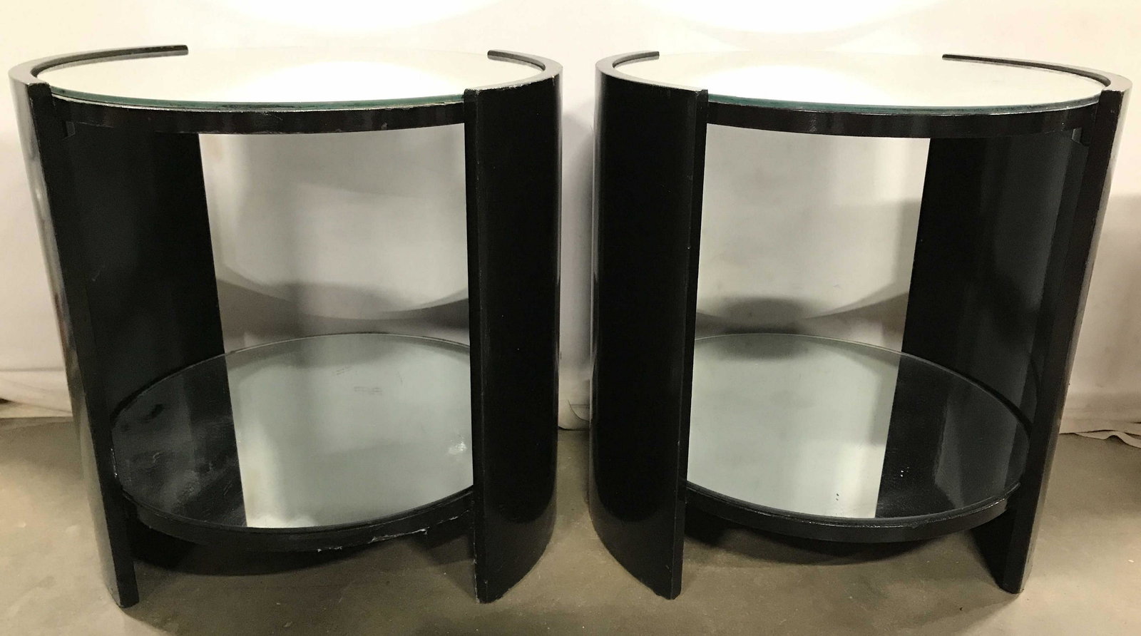 Pair Black Toned Round Mirrored Side Tables: Circa 1970's Side tables have mirrored top and lower level. Each are black toned and circular in shape. Tables appear to be wooden. Each measures approximately 21 inches tall and wide. side tables, wo