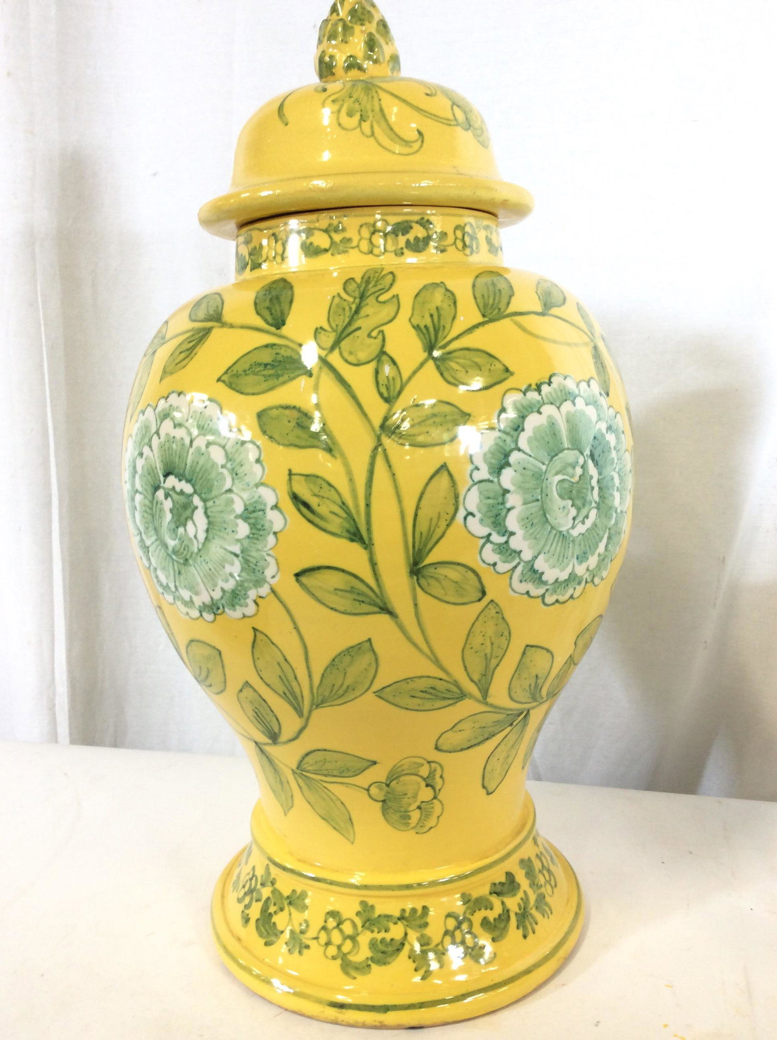 Large Floral Design Ceramic Centerpiece Lidded Urn: Vintage Urn. sunny lemon with light green laurel and stand out flower design. Acorn finial on lid, missing accent piece. Crazing to glaze consistent with exposure and age, flaking paint On underside o