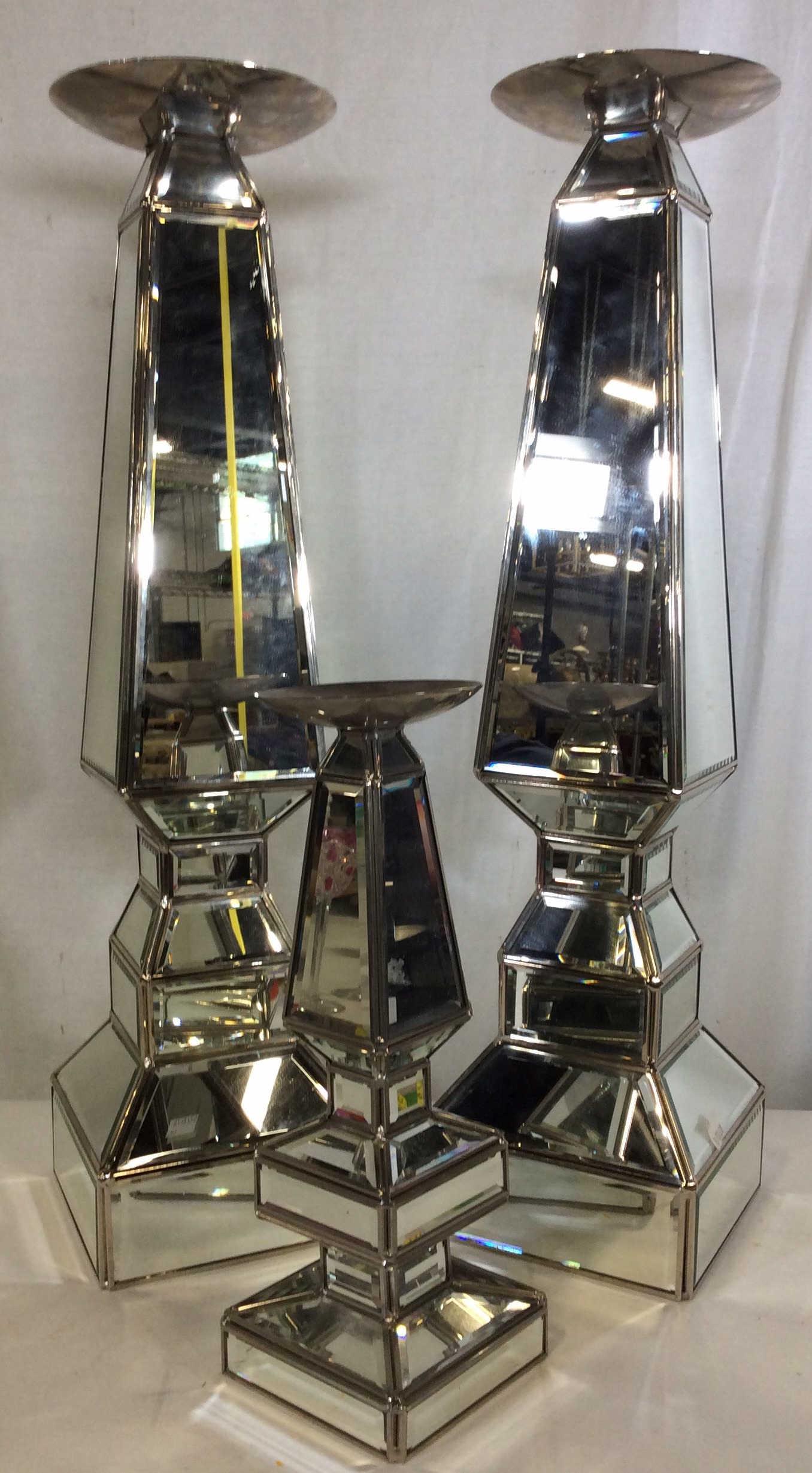 Set 3 Oversized Mirrored Obelisk Pillar: Candlestick Centerpieces. Matching pair of very tall Candlesticks, 24.5 in ht. Square base measures 6.25 x 6.25 in. Mirrored panels are beveled. Undersides have black felt, candle placement has wide 6