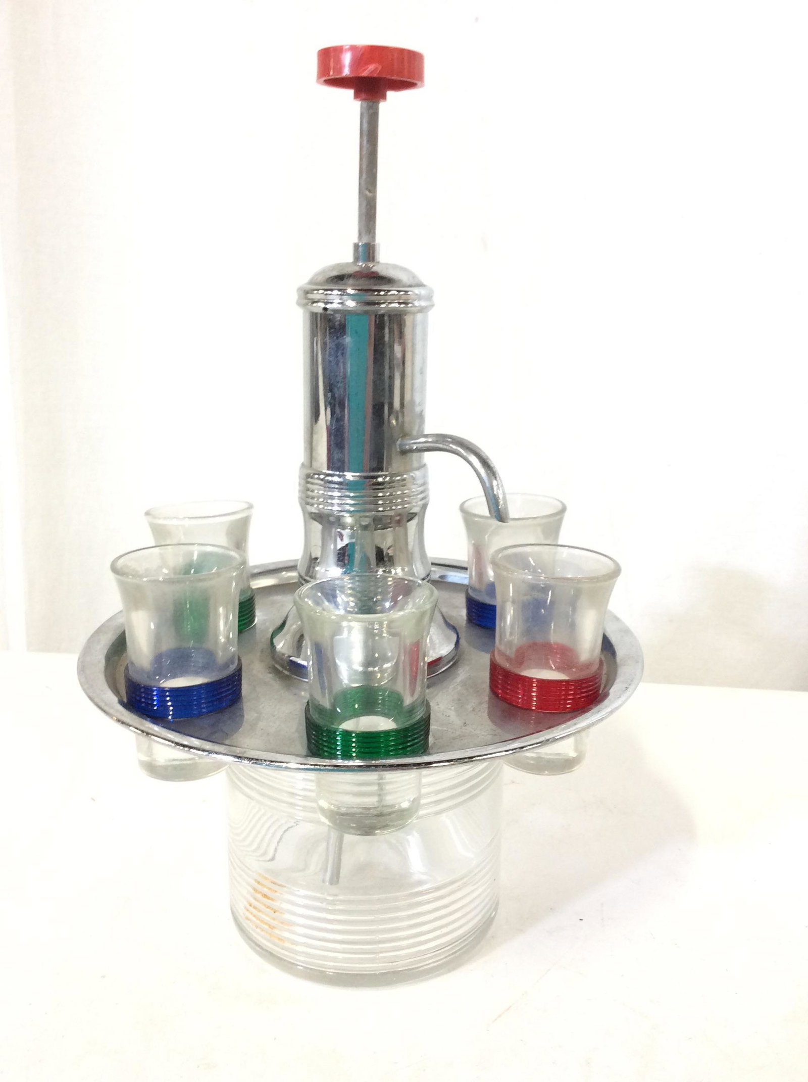 Mid Century Chrome & Glass Cordial Dispenser: Retro cordial dispenser with colorful art glass wrapped tubing, red green and blue. Cordial/ shot glasses 3 in tall. Rotating chrome tray. Twist off chrome tube to remove and fill glass jar. See pictu
