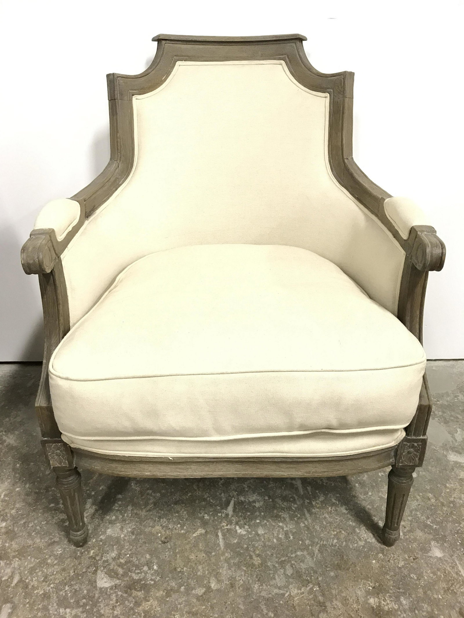 Vintage Cream Toned Upholstered Bergere Chair: Bergere is upholstered with cream toned fabric. Piece has upholstered armrests. Frame is wooden with carved detail. Piece measures approximately 28 inches wide 38 inches tall 30 inches deep. Bergere, 
