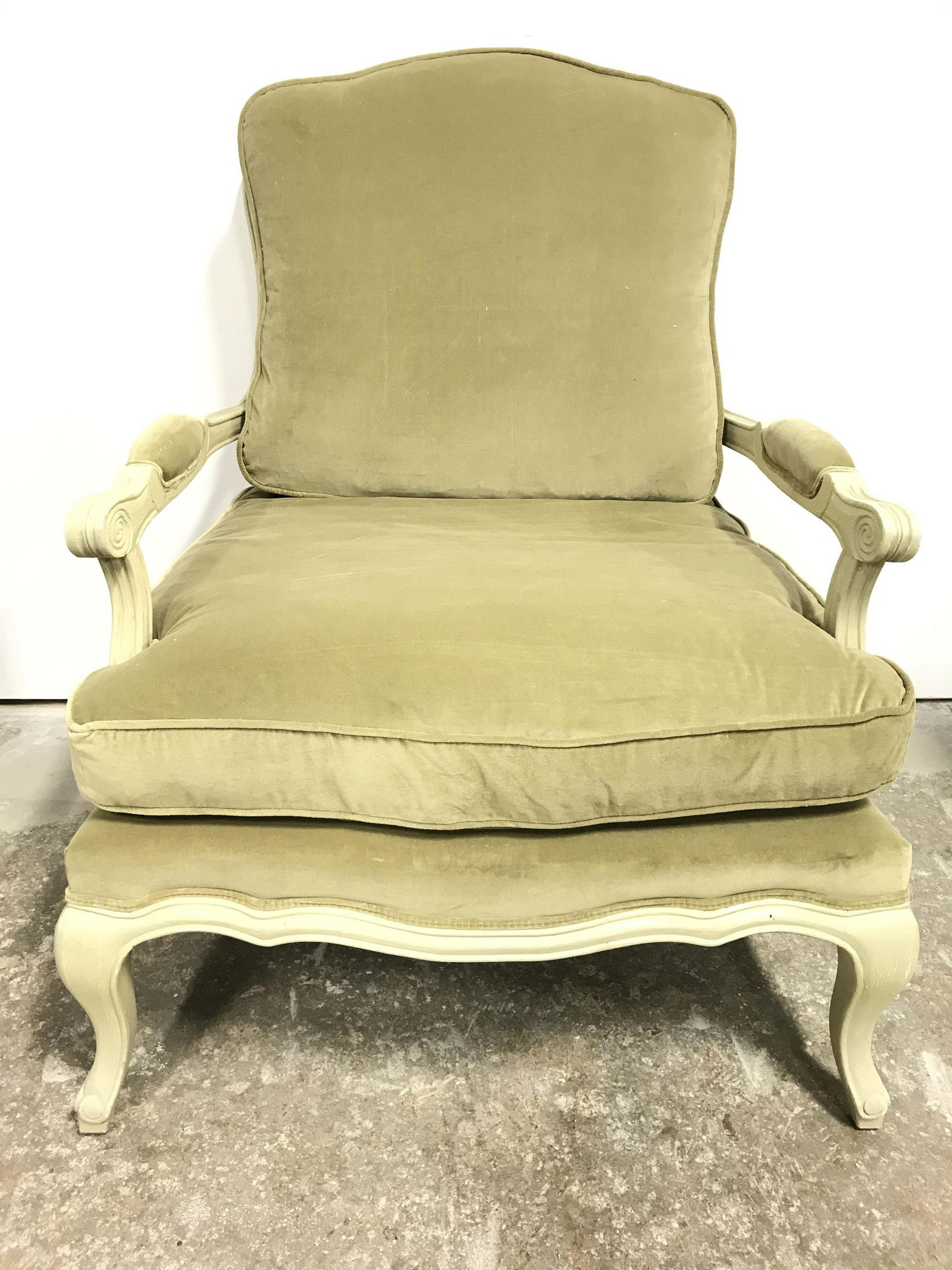 Vintage Olive Toned Caned Bergere Chair: Bergere is upholstered with olive toned fabric, possibly crushed velvet possibly silk. Piece has upholstered armrests. Frame is wooden with carved detail. Chair is double caned and has carved wooden f