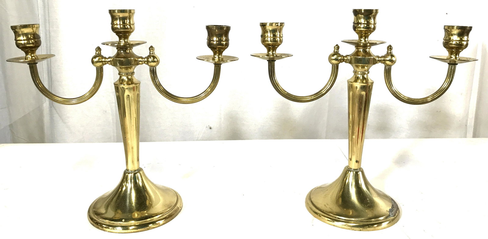 Pair Gold Toned 3 Arm Brass Candelabras: Lot includes 2 candelabras. Pieces are gold toned and brass. Each piece has 3 arms. Arms have U shaped structures. Each measures approximately 10 inches tall and wide 4 inches deep. Candelabras, Pair 