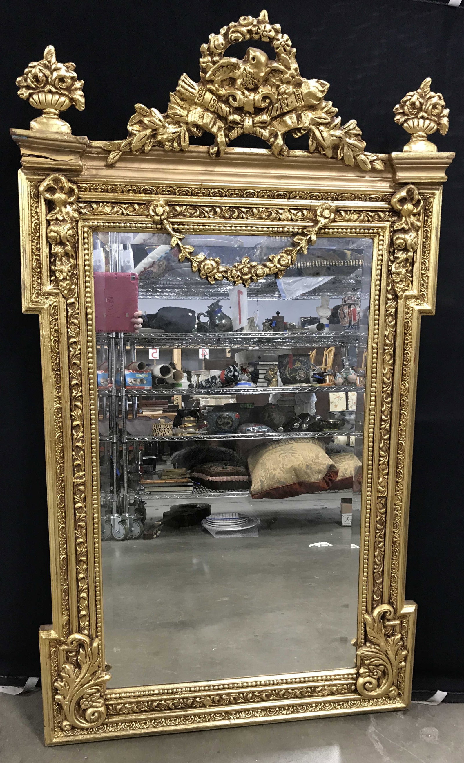 Grand Gold Leaf Carved Wood Wall Mirror: Gold leaf carved wood mirror, mirror is vintage, possibly antique. Intricate carved detailing, apex of mirror is decorated with a carved eagle atop torches, carved bouquets decorate the top right and 