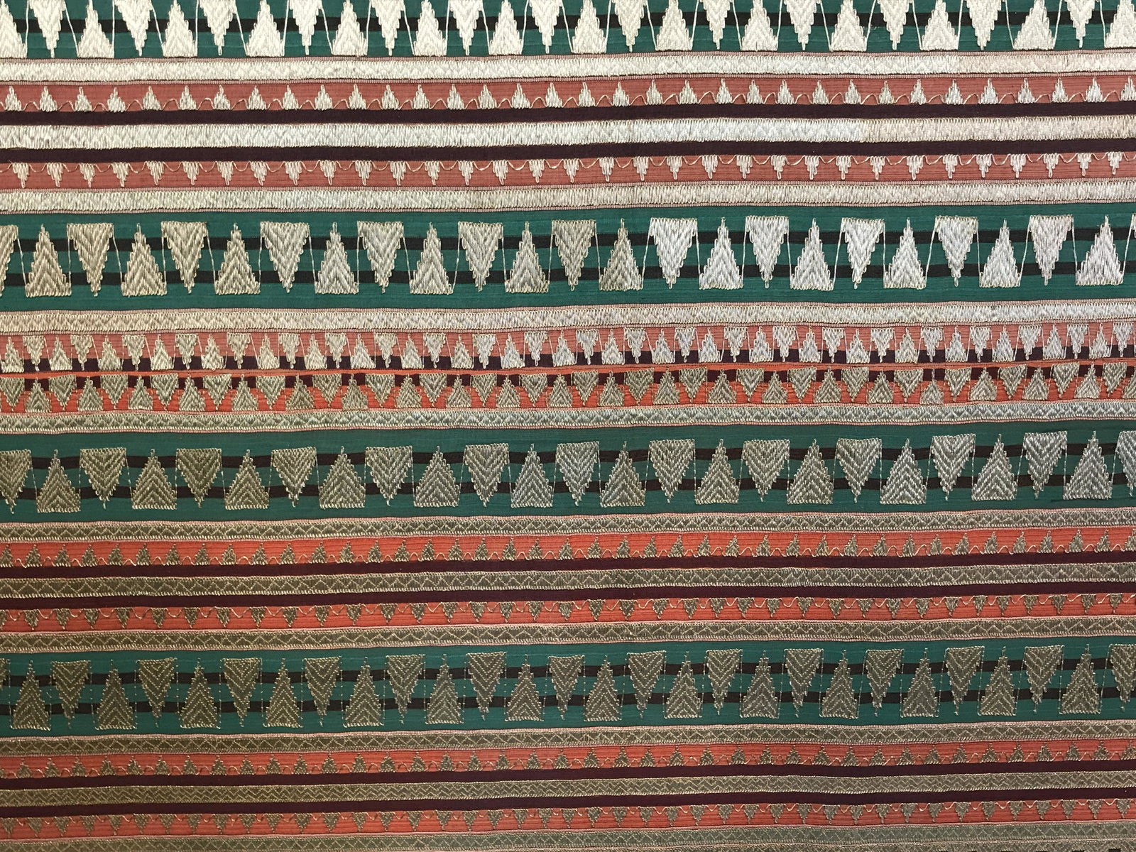 Framed Indonesian Ceremonial Sarong: Indonesian custom made hand stitched ceremonial Sarong, possibly used for a wedding, sarong made with earthy colors and metallic gold embroidery creating geometric patterns, dark wood frame, sarong in