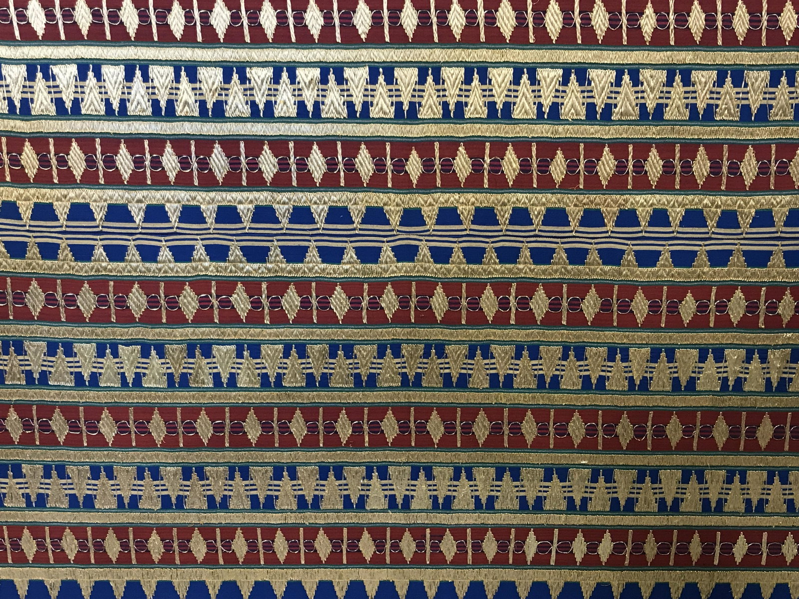 Indonesian Ceremonial Sarong: Indonesian custom made hand stitched ceremonial Sarong, possibly used for a wedding, sarong made with jewel toned colors and metallic gold embroidery creating geometric patterns, dark wood frame, saro