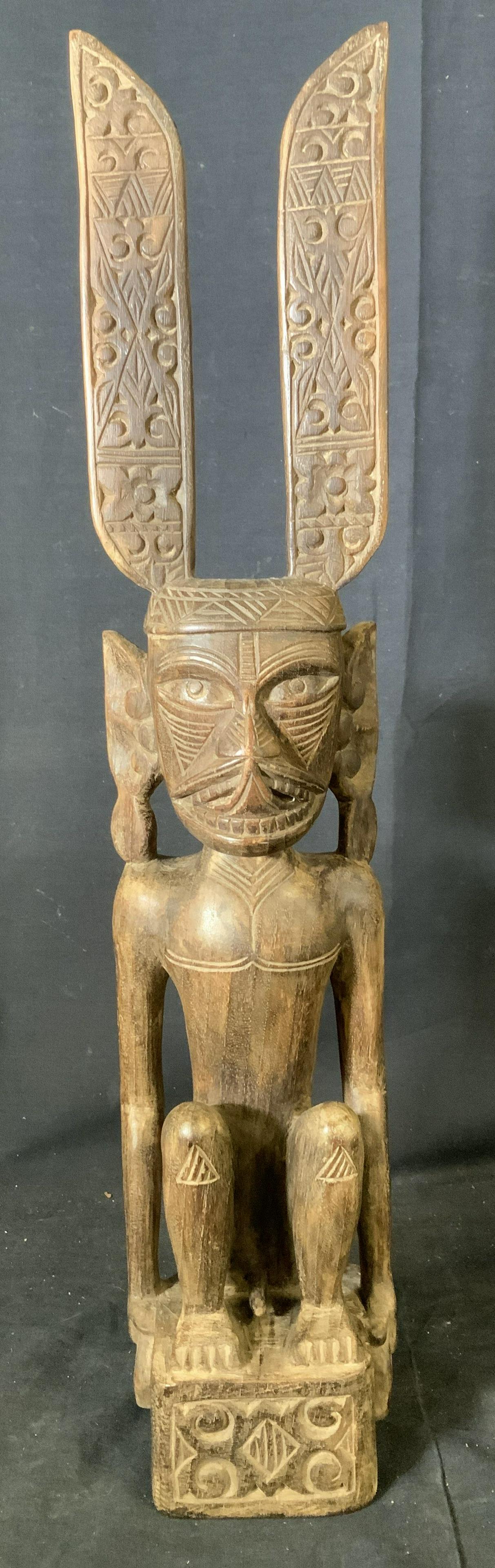 Zoomorphic Seated Wooden Sculpture: Zoomorphic seated wooden sculpture, possibly Indonesian, no apparent signatures or inscriptions, sticker to base not removed to preserve piece, a seated man wearing hat, measures 23 7/8 tall x 4 3/4 i