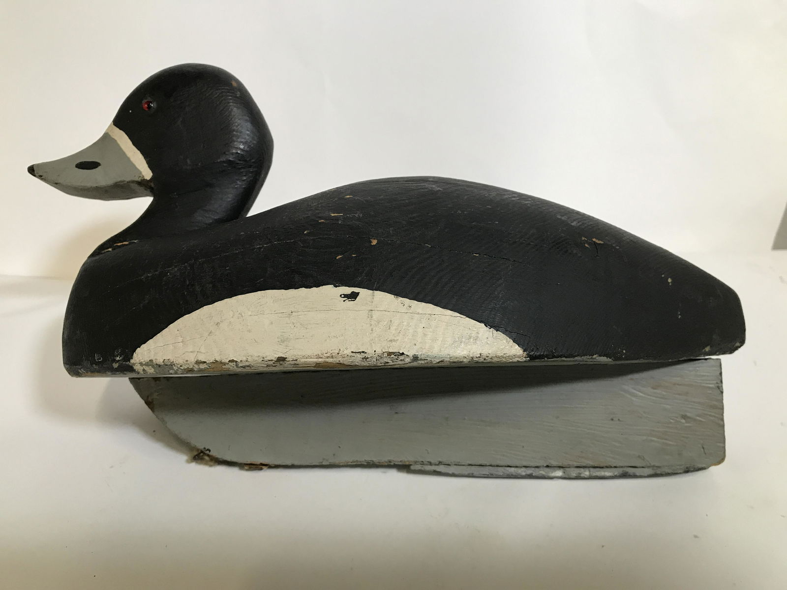 Vintage Hand Carved and Painted Duck Decoy: A vintage hand carved and painted black, white and grey duck decoy. The decoy has a rudder attached to the underside. It was presumably used for duck hunting. Additionally there are metal pieces attac