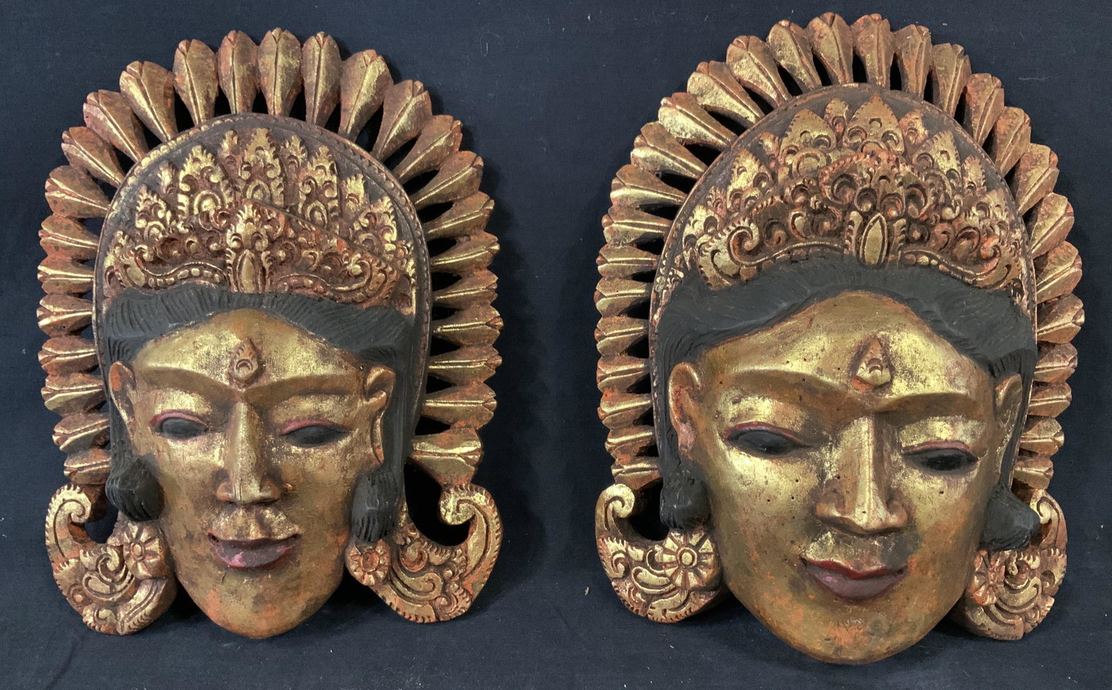 Pair Indonesian Wood Masks: Pair Indonesian Wood Masks, no apparent inscriptions or stamps, both have handles to reverse, people with intricately hand carved headdresses, painted gold and black, Both measure 11 x 8 inches, not i