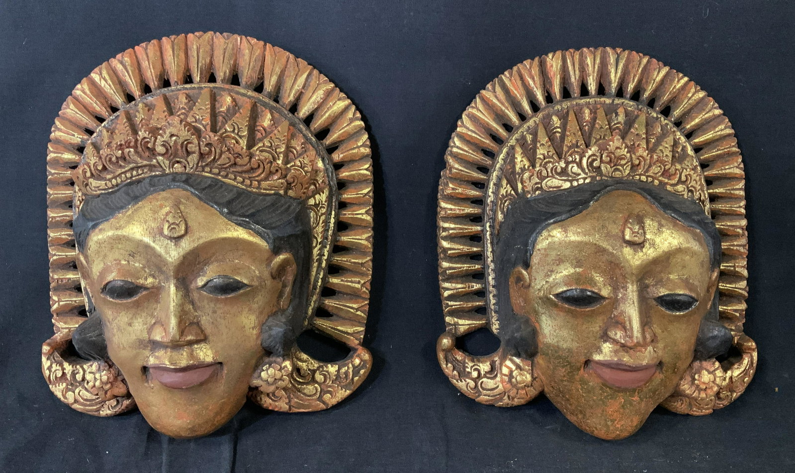 Pair Indonesian Wood Masks: Pair Indonesian Wood Masks, no apparent inscriptions or stamps, both have handles to reverse, people with intricately hand carved headdresses, painted gold and black, One measures 10 1/2 x 8 1/4 inche