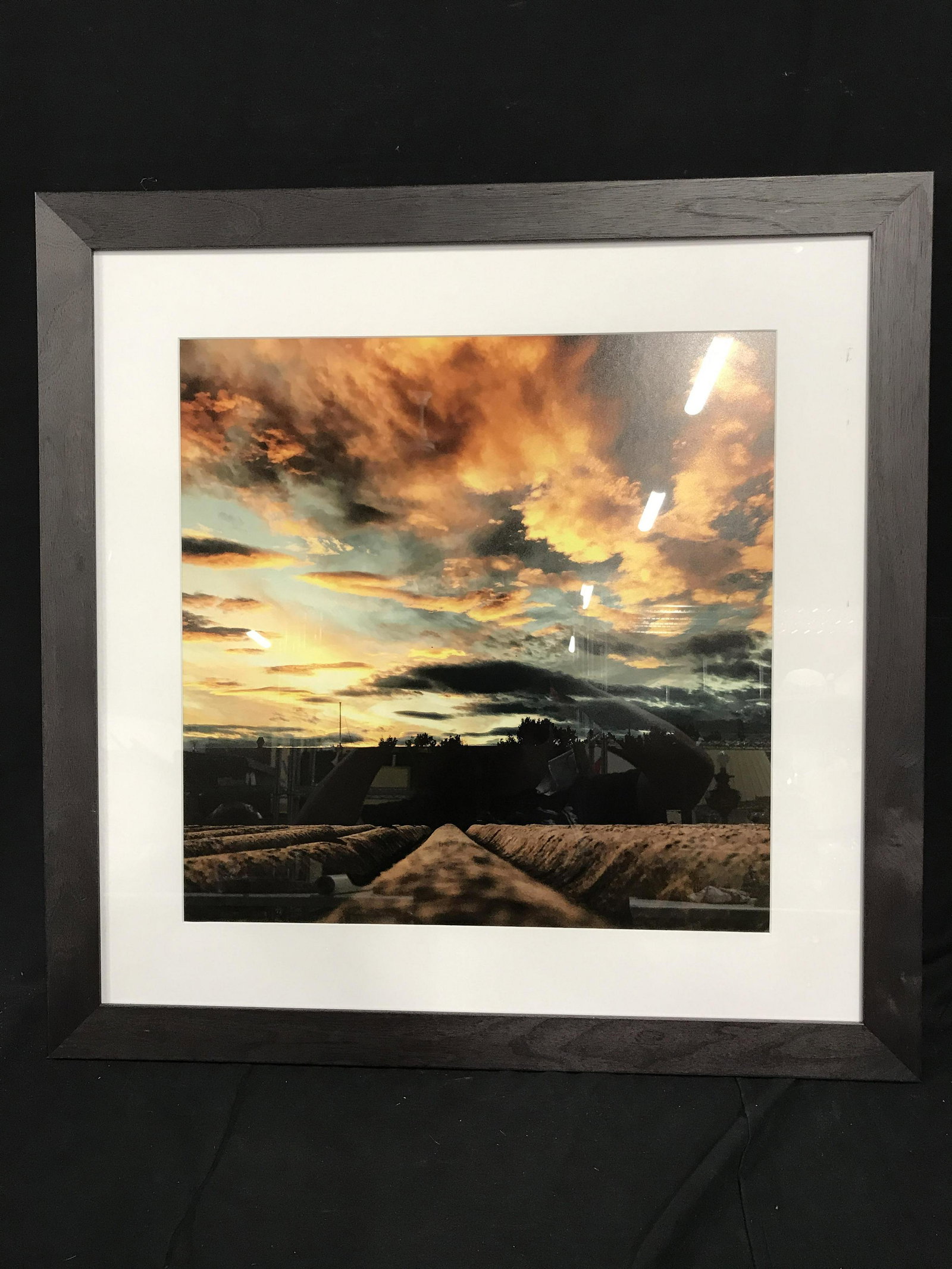Lillian August Framed Sunset Photograph: Lilian August Photograph, no apparent signatures or stamps, image depicts plowed fields under a setting sky, professionally photographed, professionally matted and framed, white matting, deep brown wo