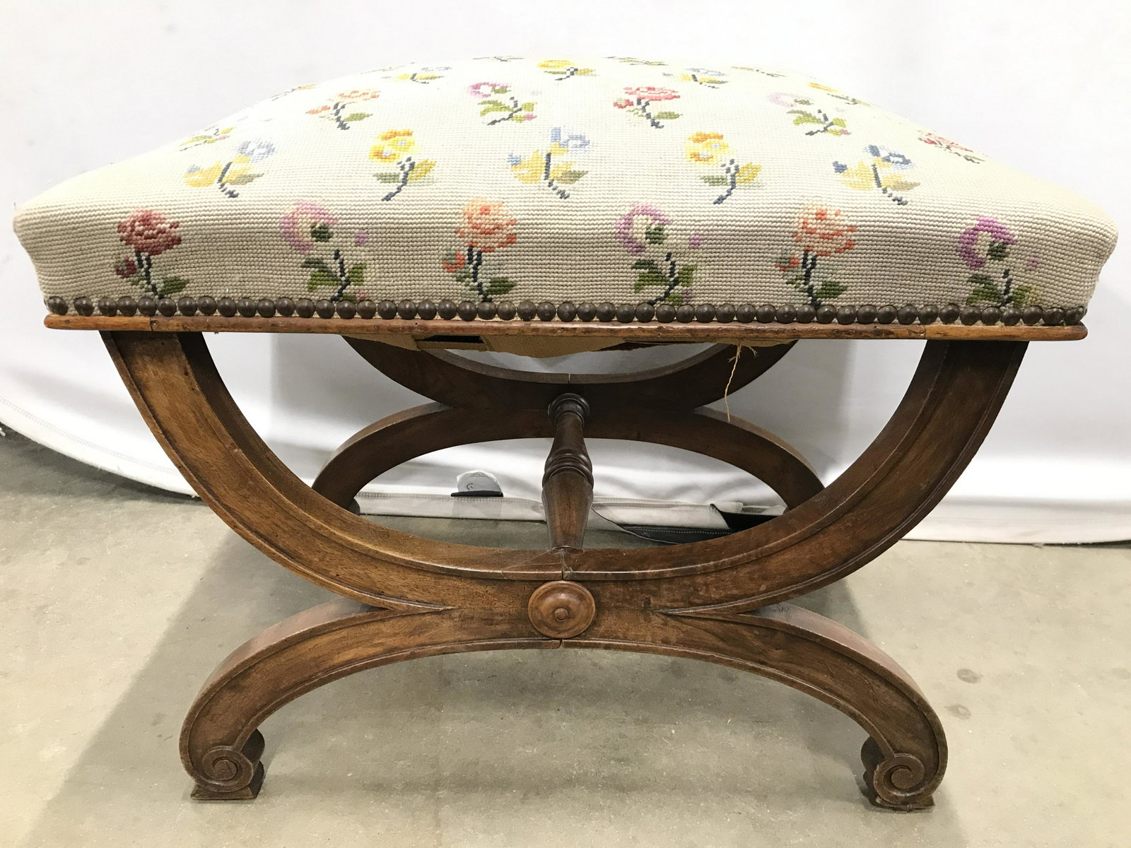 Vintage Needlepoint Upholstery Bench: Bench is vintage. Piece has multi toned floral needlepoint upholstery. Piece has carved wooden legs and nailhead Detail near edge of upholstery. Piece measures approximately 20 inches tall 23 inches w