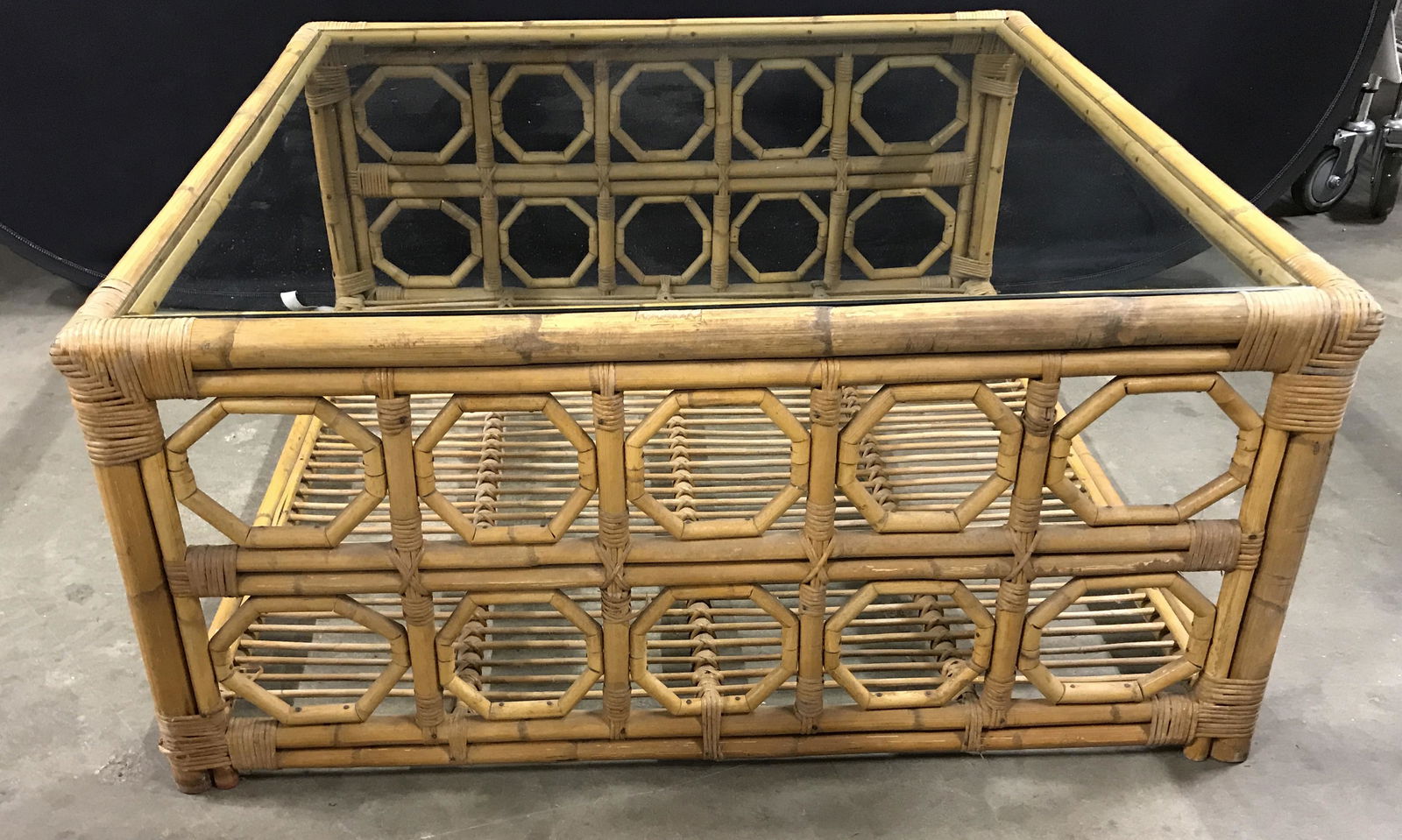 Vintage Glass Topped Wooden Coffee Table: Vintage Glass Topped table. Frame is crafted from wood and rush. Repeating Octagonal patterns flank the table. Measures approx 17.5 inches H, 39 inches W, and 39 inches deep. Wear is consistent with a